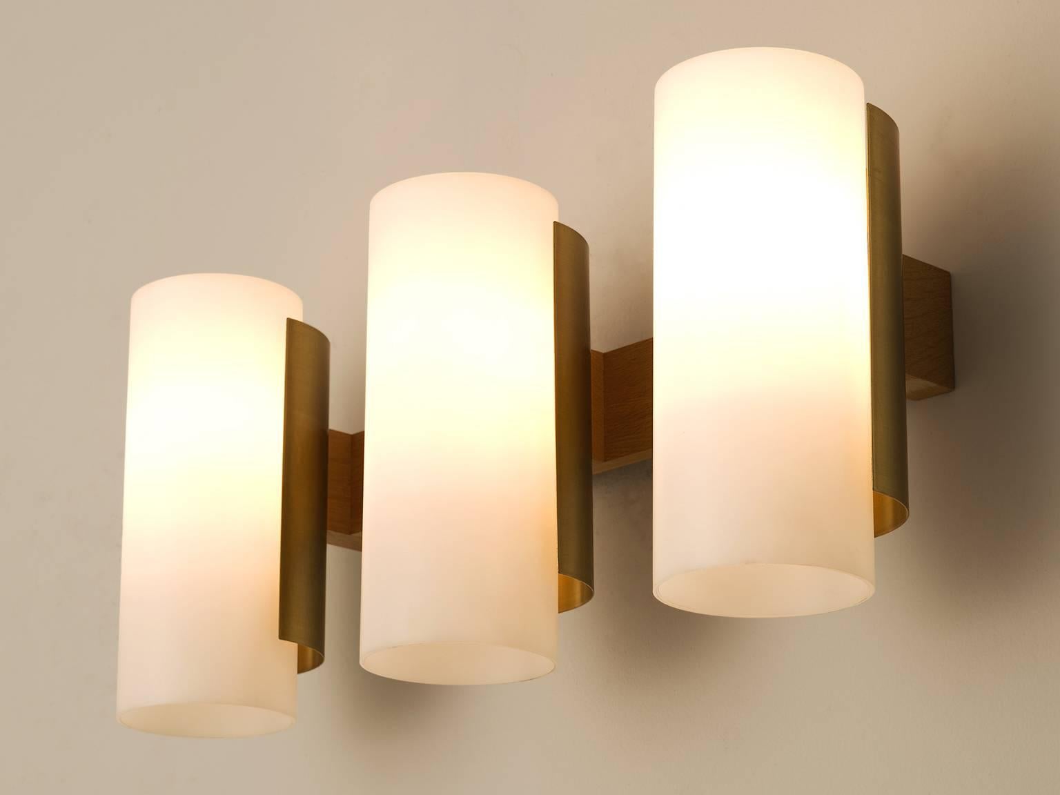 Sten Carlquis, set of eight wall lights, in brass wood and polyester, Sweden, 1960s. 

Set of eight large wall lights. Each light consist three cylindrical white shades, which are hold by a brass frame. The wall fixture is made out of wood. The