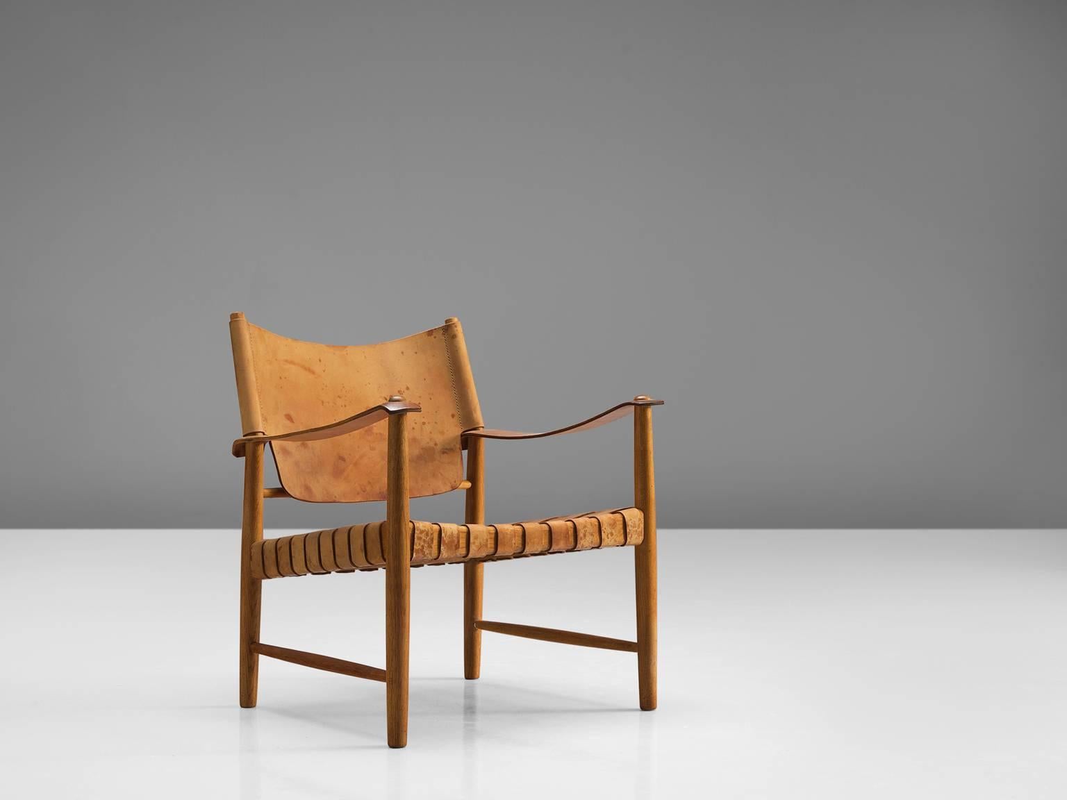 Safari chair, leather, oak, Denmark, 1950s

This elegant safari chair features wonderful patinated leather on both seat and back. The patina on this chair creates a vibrant look and the straps in the seat form a thick, well-constructed yet