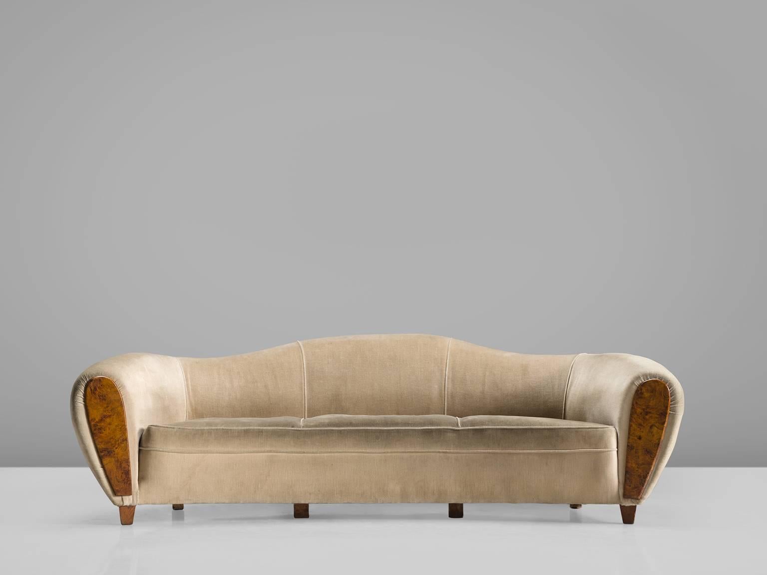Sofa, white to beige fabric and burl wood, France, 1940s.

This voluptuous sofa is executed with burl and and a velvet like fabric. The sofa has a curved back and very thick and wide armrests that are covered with a burl front. The sofa has small