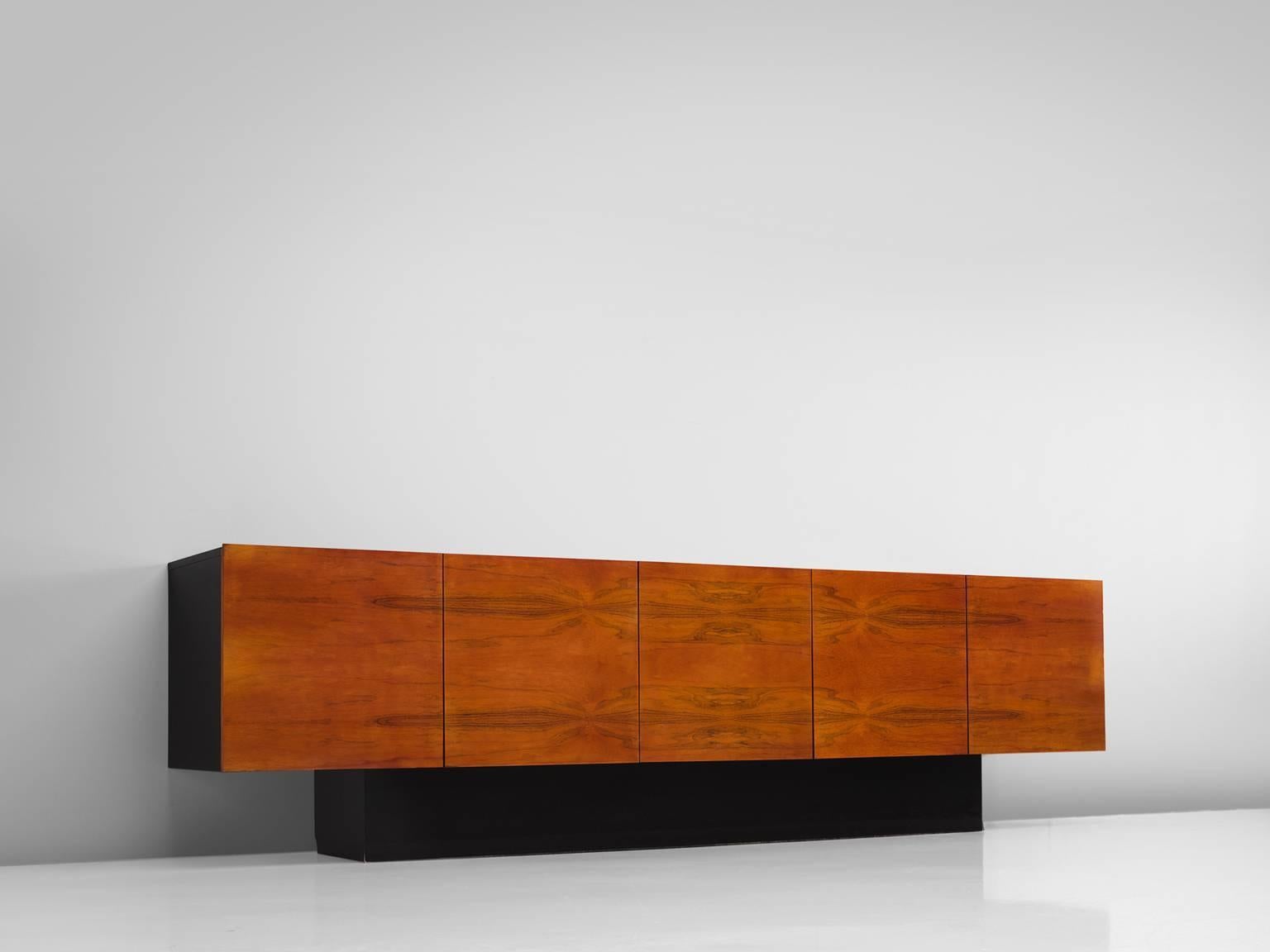 Credenza in the style of Milo Baughman, wood, rosewood, United States, 1970

This large sideboard is part of the midcentury design collection. The side board features a black pedestal base and four bookmatched doors that feature a wonderfully warm