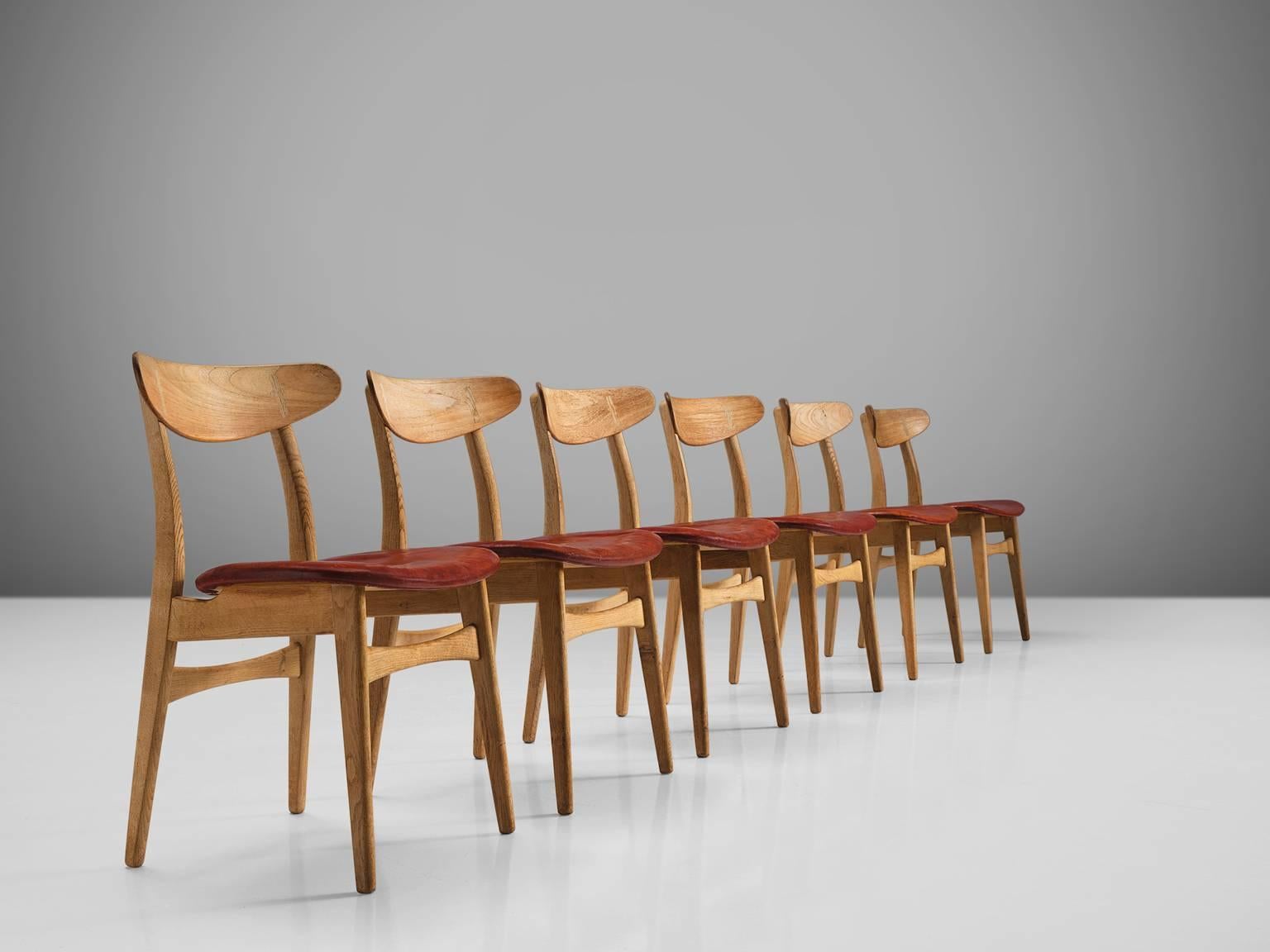 Hans J. Wegner for Carl Hansen & Søn, set of six 'CH 30' dining chairs, oak, teak, leather, 1954, Denmark.

This set of six dining chairs is upholstered with deep red leather that has patinated over time. The frame is made of oak whereas the back is