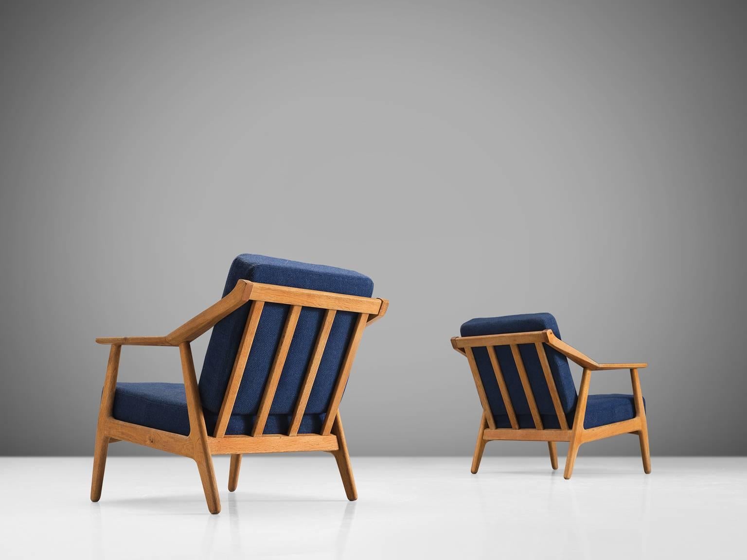 Armchairs, oak, blue fabric, Denmark, 1960s

This set of sculptural armchairs has a slatted back and four circular legs. The armrests are executed with an angle in the middle and this is also the place were the back legs join the frame. The solid