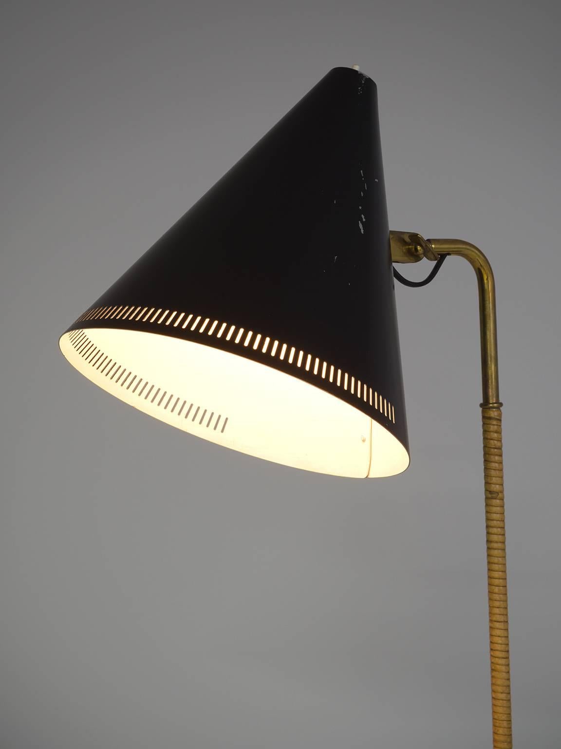 Paavo Tynell lamp for Idman, model K10-10, aluminum, cane, brass, Finland, 1940s

This delicate floor lamp has a few distinct features. The black coated shade features delicate holes on the rim that have make the shade appear less solid. The light