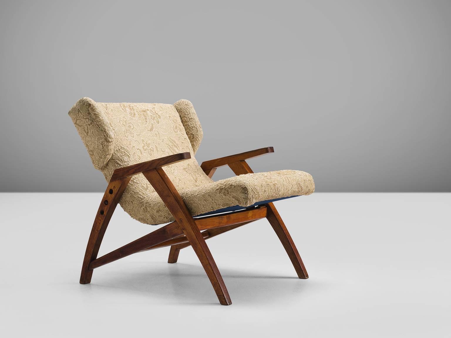 Easy chair, wood, beige brown fabric, oak, Czech Republic, 1940s.

This strong oak wingback chair is designed with a slightly sloped back in order to provide sitting comfort. The chair features small, geometric wings that are seperated from the the