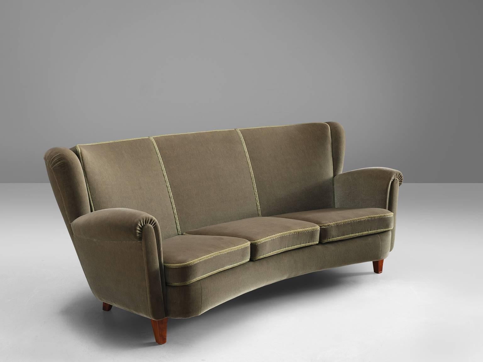 Three-seat sofa, in wood and green-grey velvet, Denmark, 1950s. 

This sofa shows typical Danish design traits such as exquisite craftsmanship and modest aesthetics combined with comfort. The settee features a soft, curving back with small wings