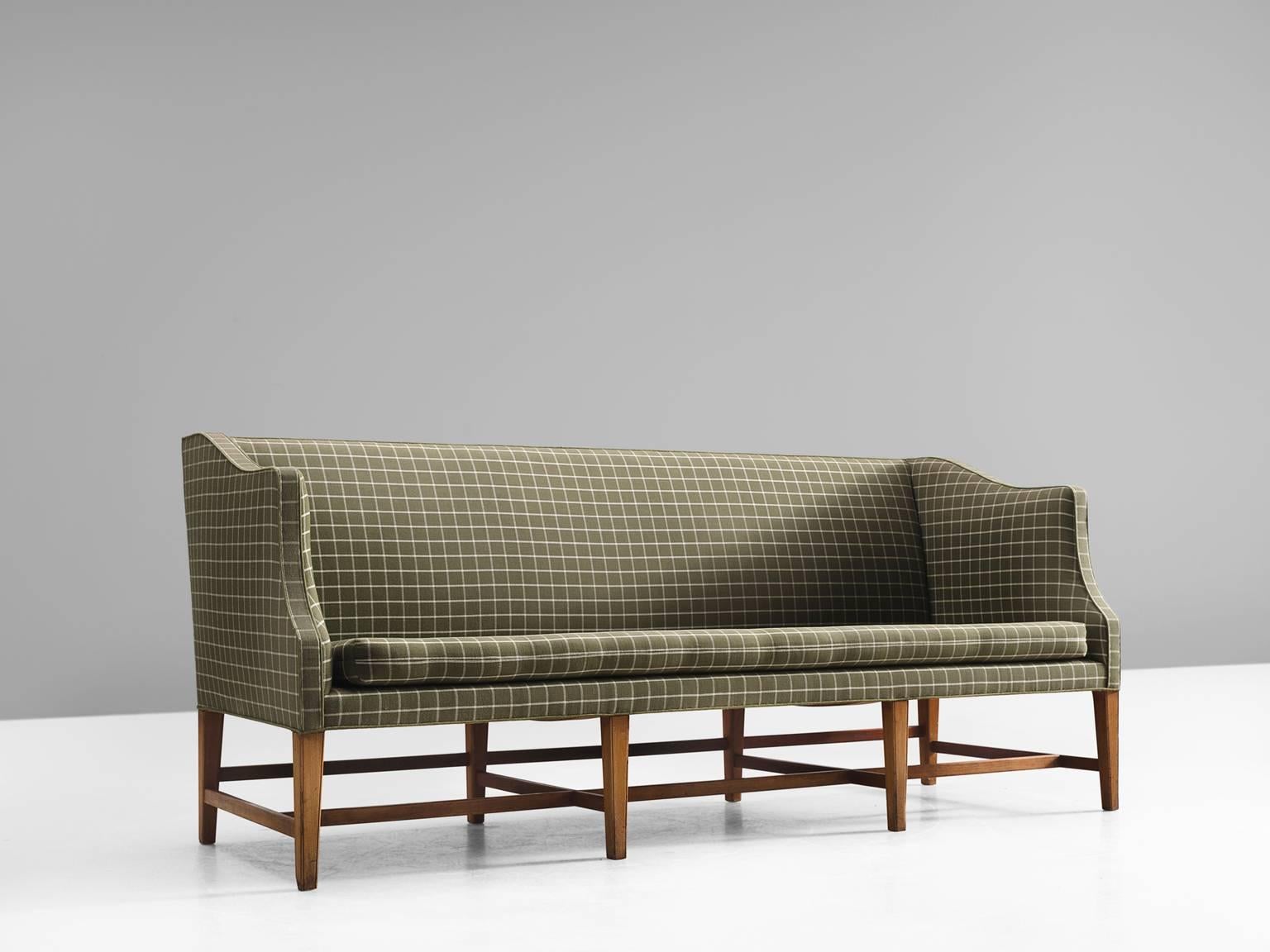 Danish cabinetmaker, fabric, mahogany, Denmark, 1950s. 

This free-standing three-seat sofa with has eight profiled mahogany legs. The sofa is upholstered with a white and green checked fabric. The sofa features ornate forms and shapes and holds a