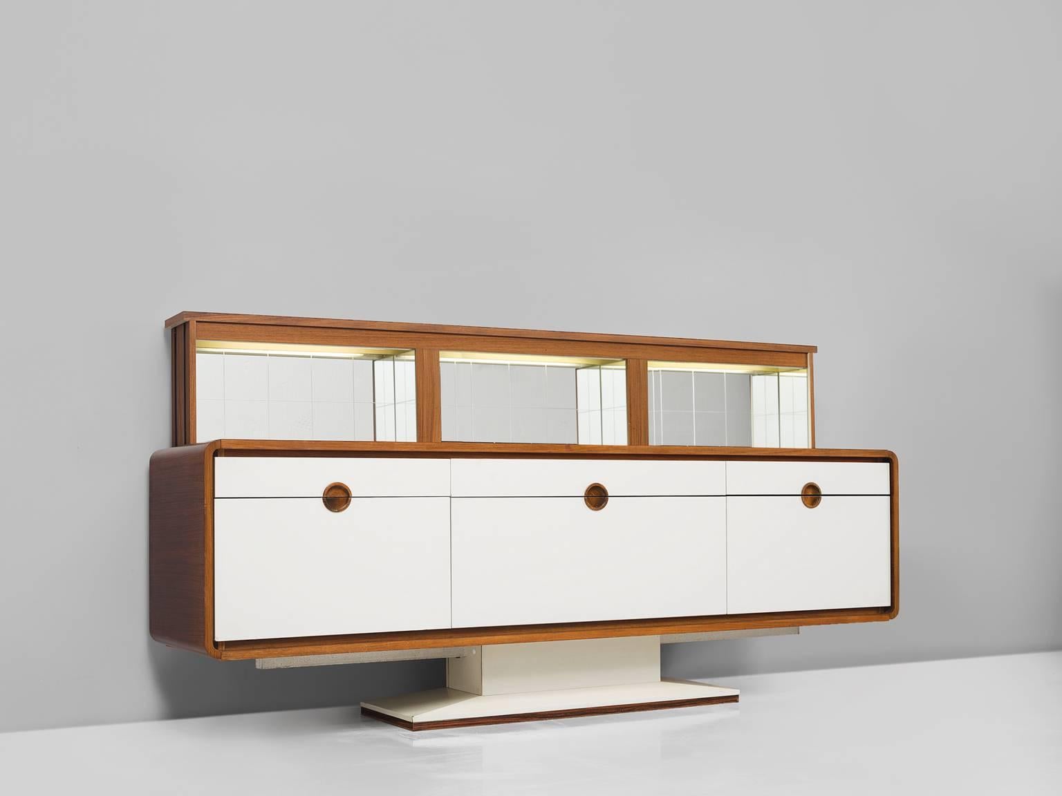 Credenza, wood, mirror, Europe, 1970s.

This piece has an Art Deco feel to it and is luxurious and well-executed. This cabinet is defined by a graphic play of a clean white planes and a warm neutral wood, giving this piece a refined finish. This