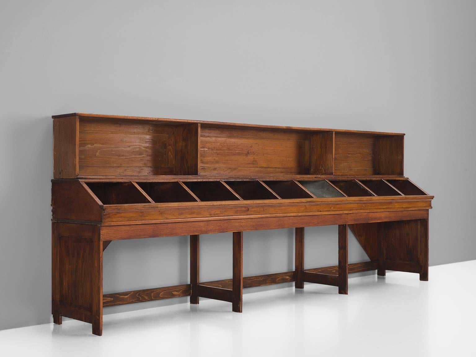 Showcase, wood, Europe, 1940s.

This long and functional showcase is executed in oak. The base of this vitrine is simple and is made with eight straight legs. The cabinet has nine small storage spaces and on top there are three large cabinets of