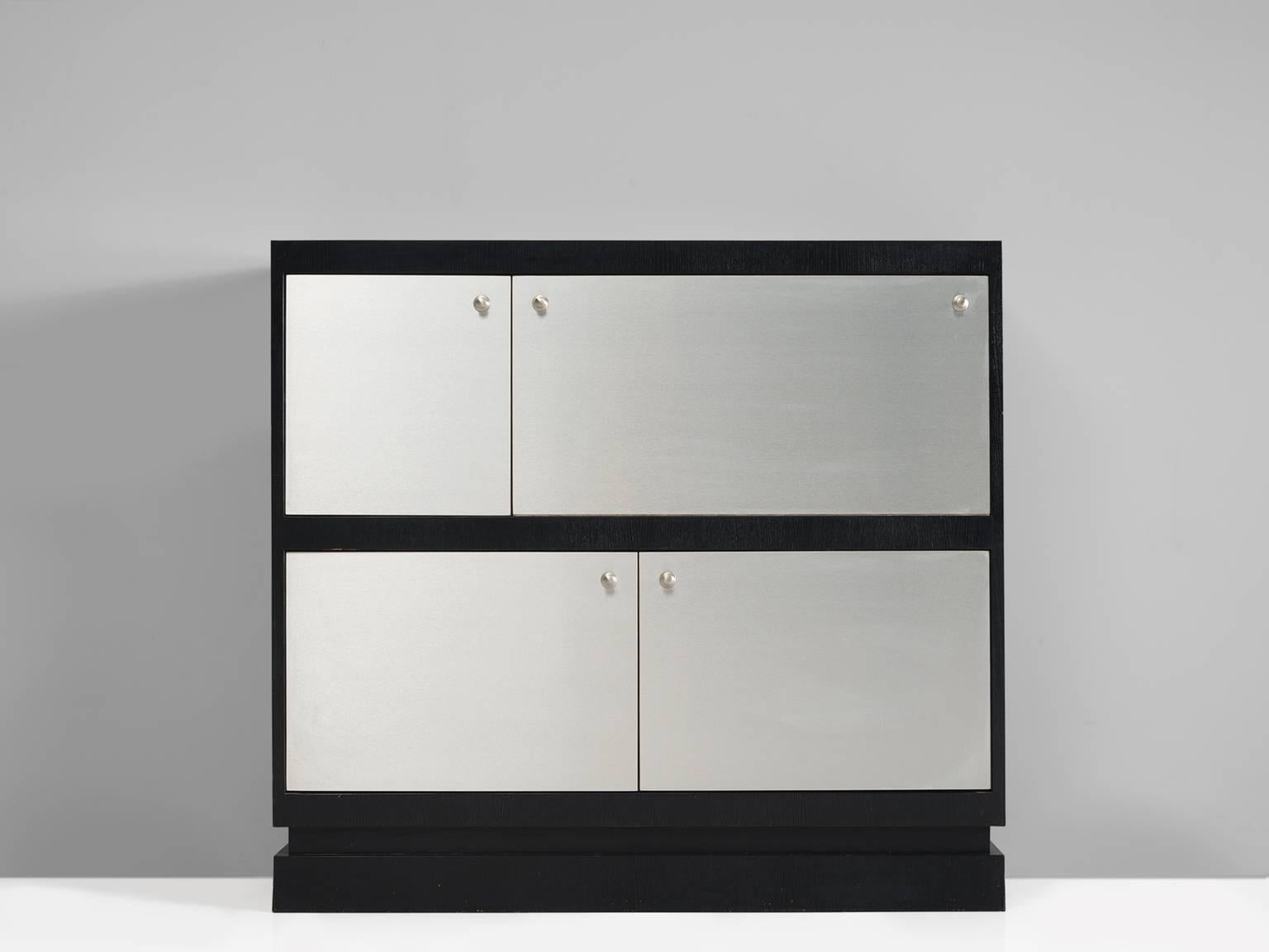 Cabinet, plywood, aluminum, Belgium, ca. 1970.

This high cabinet features four asymmetrical doors. Three of them are normal doors and one folds downwards and can be used as a liquor hatch. The frame and body of the cabinet is executed in a black