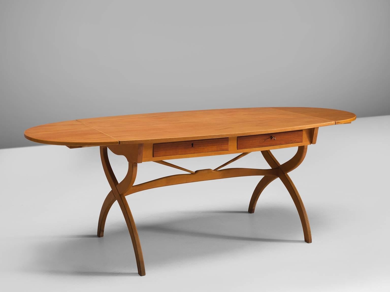 Børge Mogensen, writing table, teak and oak, Denmark, 1960s. 

This oval drop-leaf table by Danish Designer Børge Mogensen. The table consist of an X-shaped base with two legs and an oval top with drop-leafs. Under the top are two drawers that are