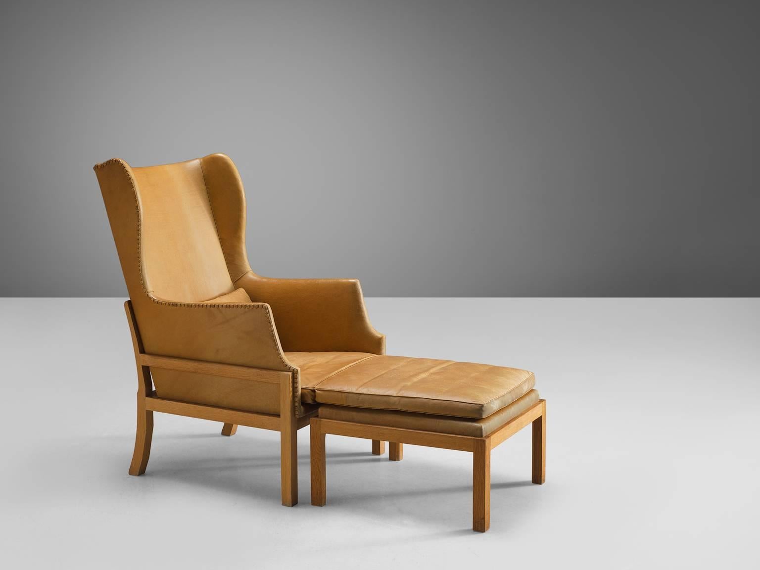 Mogens Koch for Ivan Schlechter, wingback chair and ottoman, cognac leather, mahogany, Denmark, design 1936, manufactured 1970.

Elegant and comfortable armchair in mahogany and leather by Mogens Koch. This lounge chair was designed with high