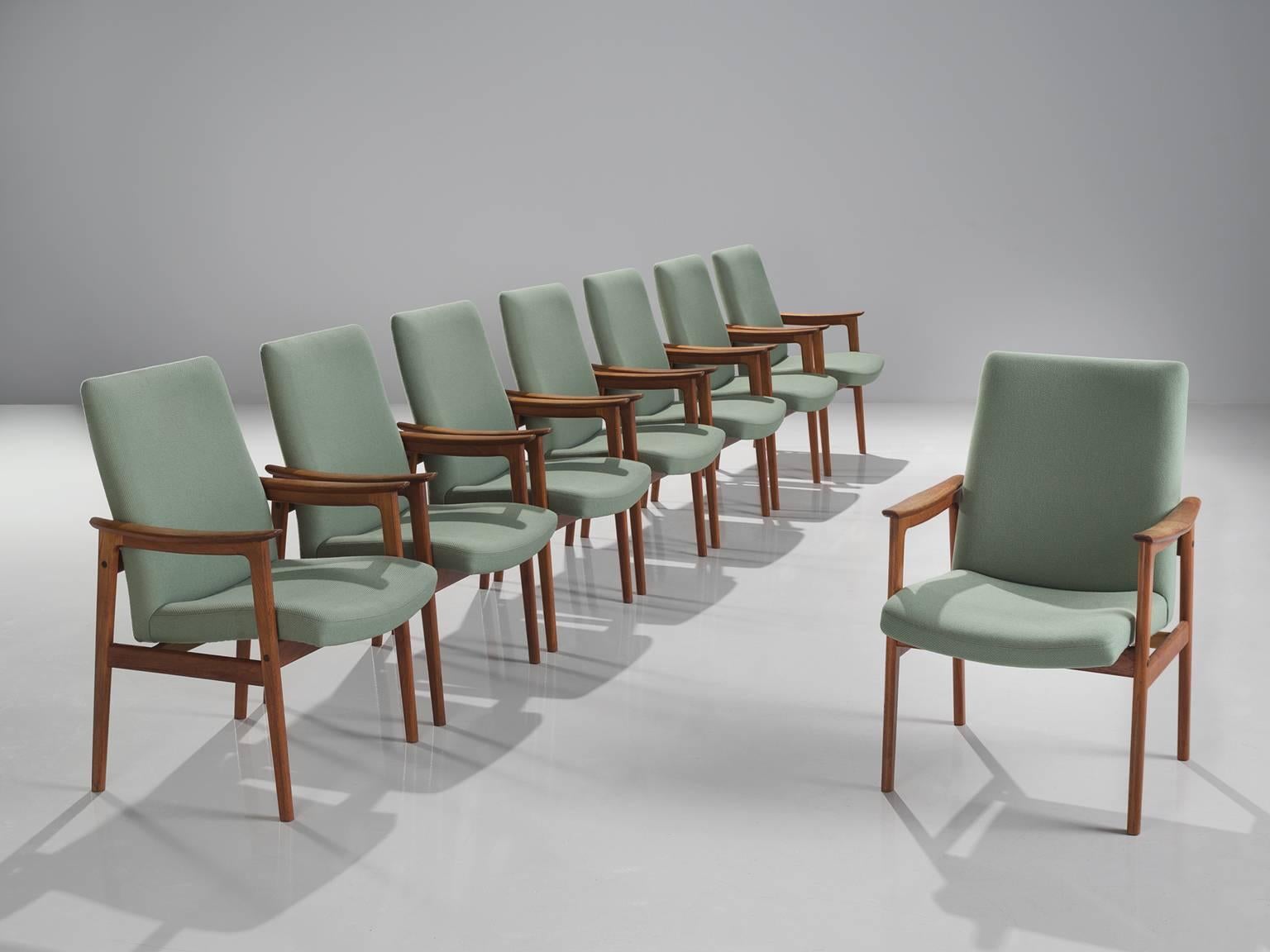 Set of eight armchairs, teak and mintgreen fabric, Scandinavia, 1950s. 

These elegant teak dining chairs with armrests are both stately and modest. These Scandinavian chairs have a teak frame with a beautiful visible grain. Nicely curved armrests