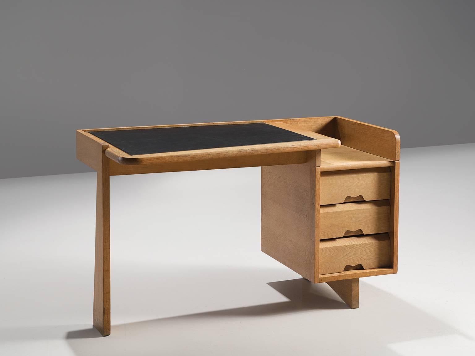 Guillerme et Chambron, desk, oak and leather, by France, 1960s. 

This small desk is designed by the French designer duo Guillerme and Chambron. This writing desk holds the characteristic decorations and lines of this duo such as the decorative