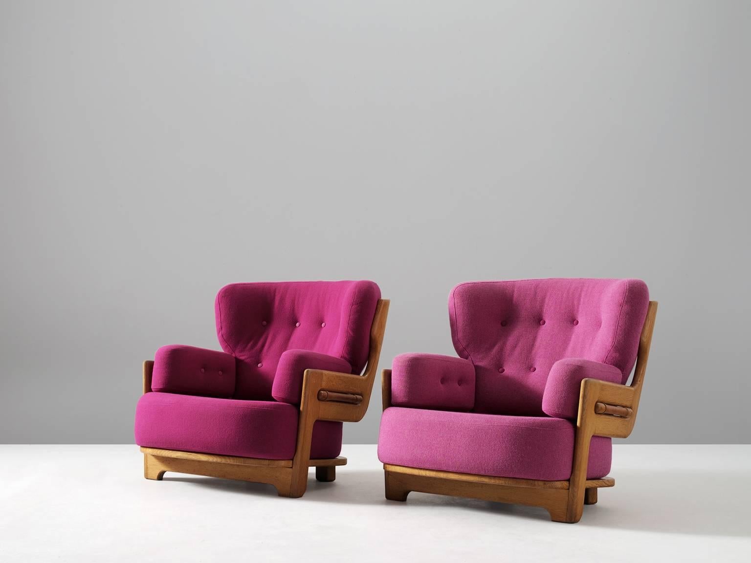 Guillerme et Chambron, set of two lounge chairs, oak and pink fabric, France, 1940s. 

Set of two extraordinary Guillerme and Chambron armchairs in solid oak with the typical characteristic decorative details such as the leather horizontal bars on