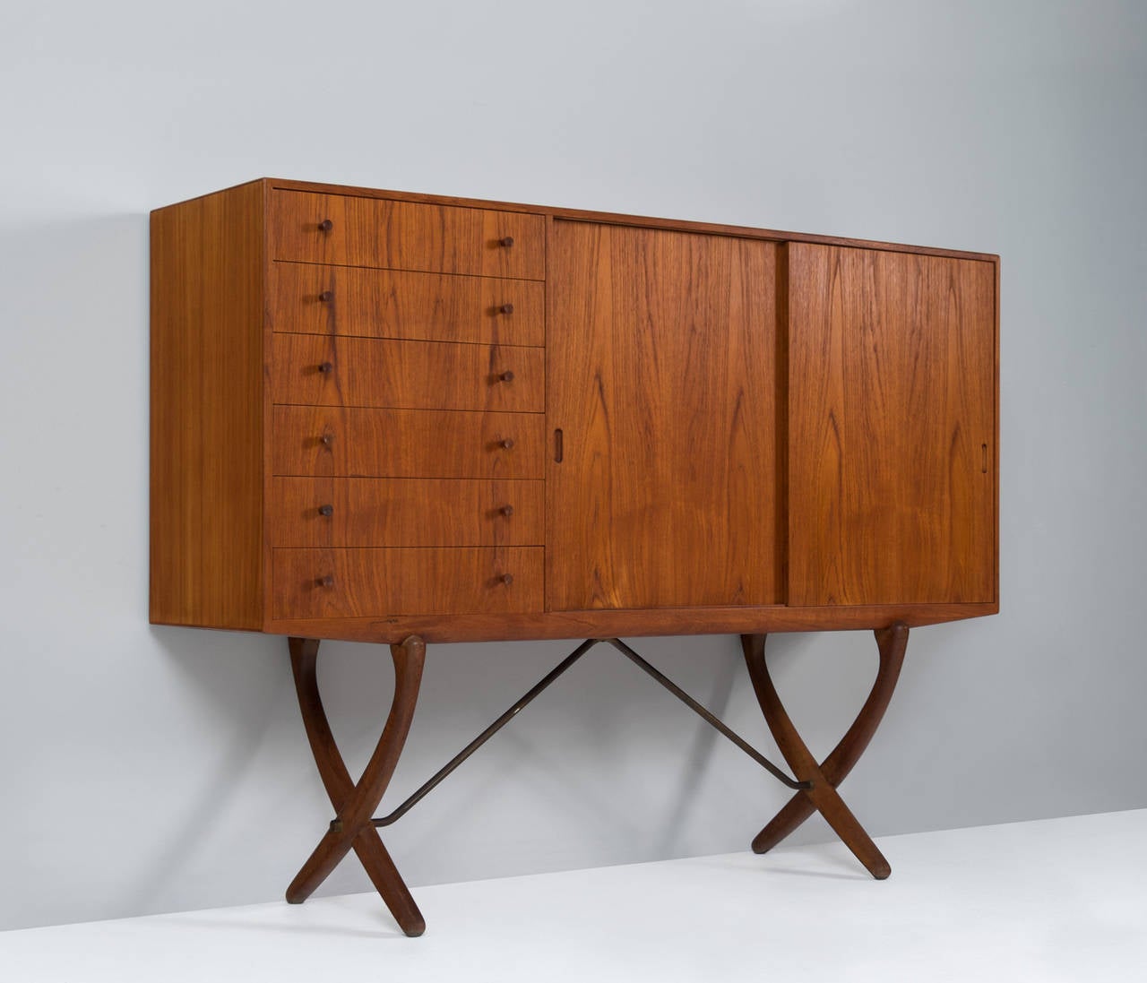 Hans J. Wegner for Carl Hansen, sideboard, teak, oak and brass, by Denmark, 1950s.
 
Rare teak and oak highboard with X-leg base by Hans Wegner. The outside is veneered with teak veneer with a hardwax finish, based on the original expression, the