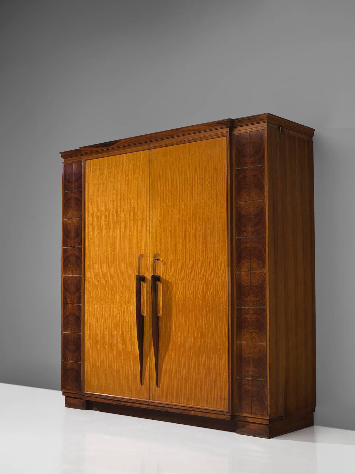 Cabinet, mahogany, satinwood, Italy, 1930s. 

This early Italian cabinet stands out due to its finesse and refinement. The cabinet has may hand-carved exquisite details such as the handles that are carved as a sharp, long drop. The front of the