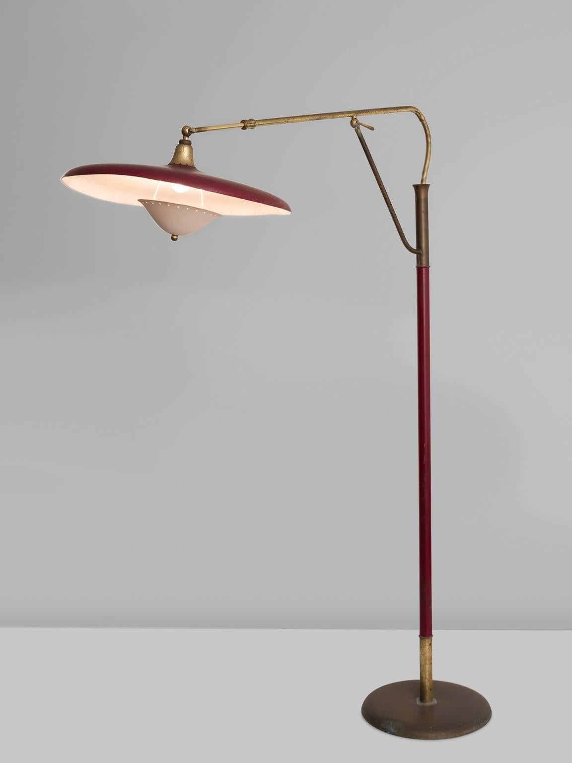 Floor lamp by Arredoluce, cast iron, varnished tubular steel, brass, lacquered aluminium, Italy, 1950s. 

This red and brass floor lamp features a circular base and a slender, long shaft. From the shaft a bended brass handle that holds the round