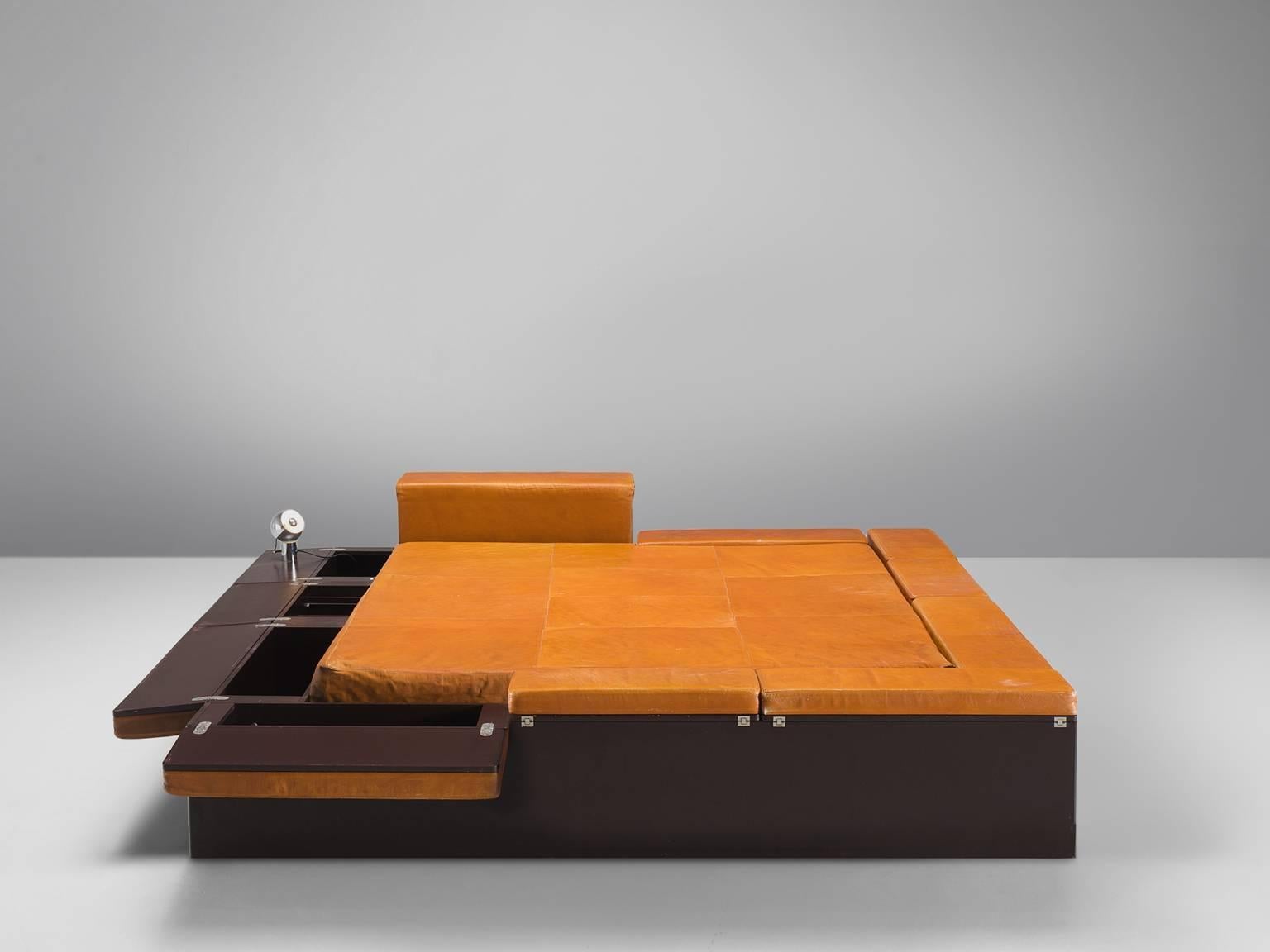 Bed with storage facilities and three Reggiani lamps (stamped), leather, plywood, metal, polyester, Italy, 1970s. 

This bed is executed in cognac leather and is built on a storage base. On each side of the bed are small lamps attached by