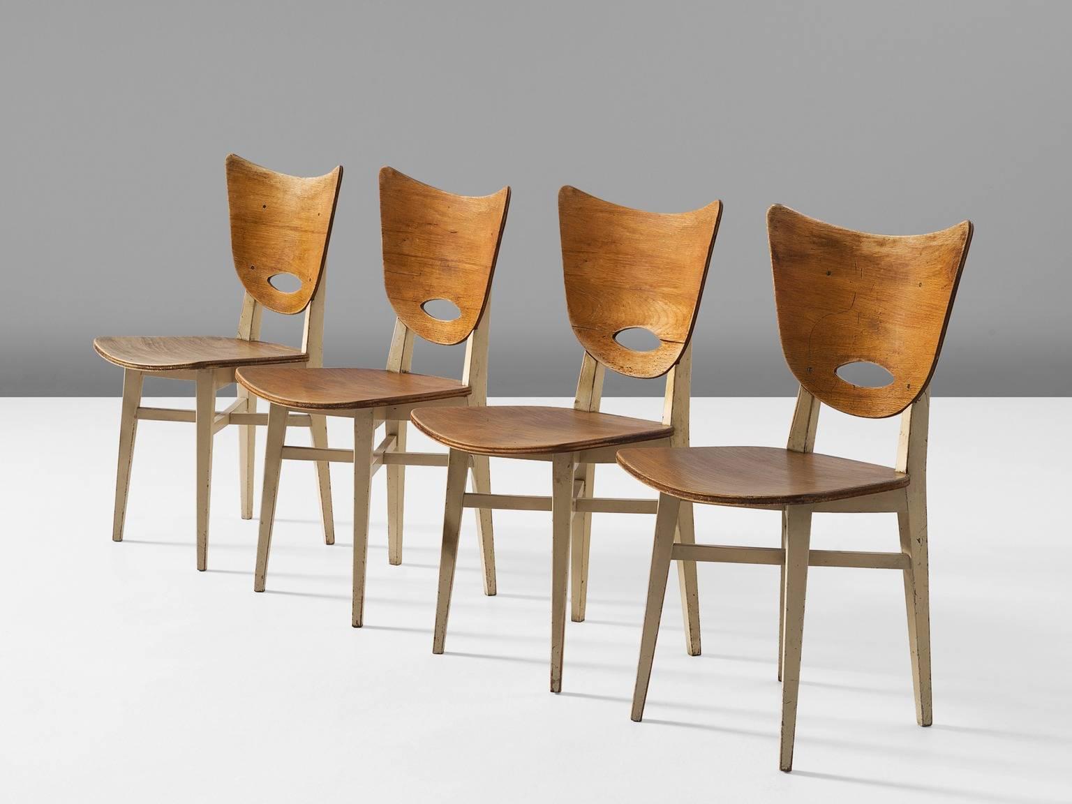 Set of four chairs, in beech, Europe, 1950s. 

Set of four dining chairs in stained beech. These chairs show nice organic lines in the back and seating, accompanied by a traditional frame. The white lacquered frame makes a nice contrast to the brown