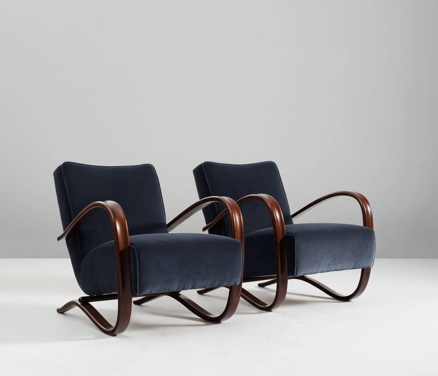 Jindrich Halabala, pair of armchairs, beech and fabric, Czech Republic, 1930s. 

These chairs have a very dynamic appearance, due the curved base that ends fluently in the armrests. The dark brown stained wood nicely combines to the dark blue