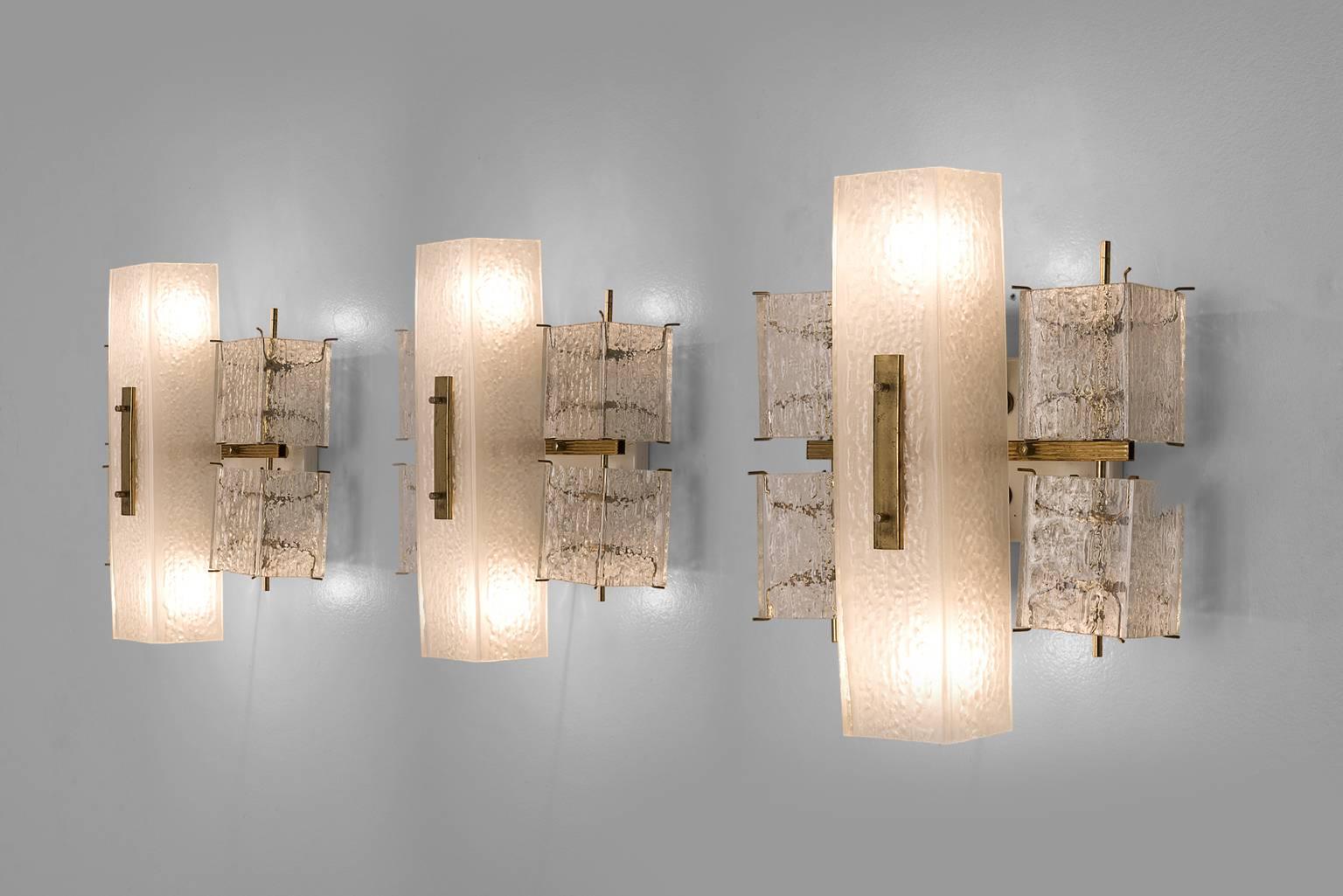 Wall lights, in glass and brass, Europe, 1970s. 

This elegant square wall lights features four small rectangular structured glass shades and a rectangular opaque middle section. The frame is made of brass and holds small brass pins on which the