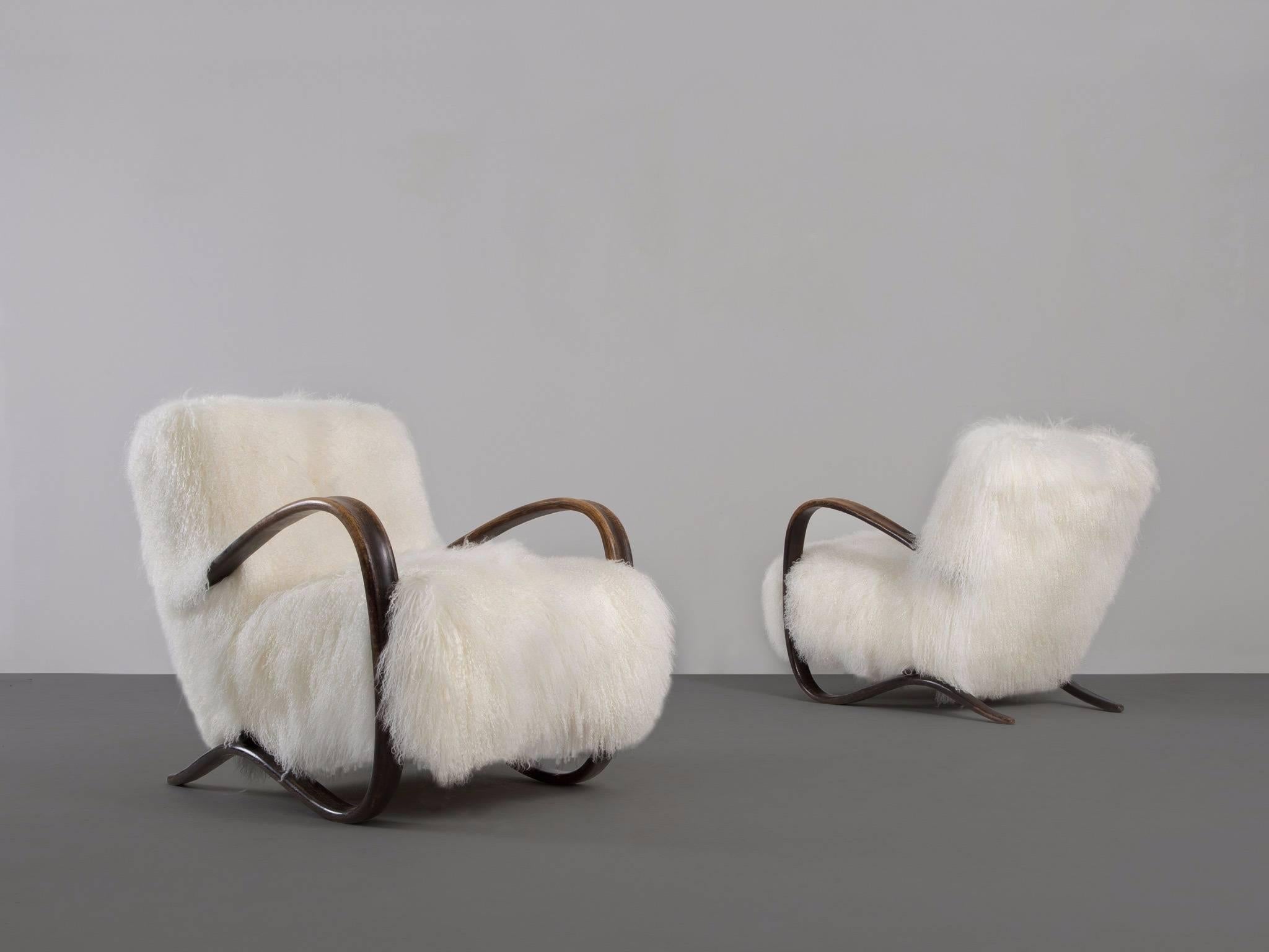 Pair of lounge chairs, in stained beech and sheepskin, by Jindrich Halabala (1903-1978), Czech Republic, 1930s. 

Extra ordinary pair of white easy chairs with Tibetan lambswool upholstery. These chairs have a very dynamic and abundant appearance.