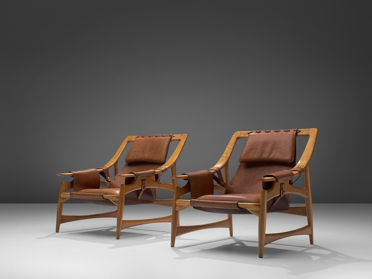 W. Andersag, set of 2 lounge chairs, teak and saddle leather, Italy, 1960s.

These chairs are very dynamic due it's design and shapes. The teak frame shows beautiful lines. The frame and construction reminds of the sturdy hunting chairs. Thick