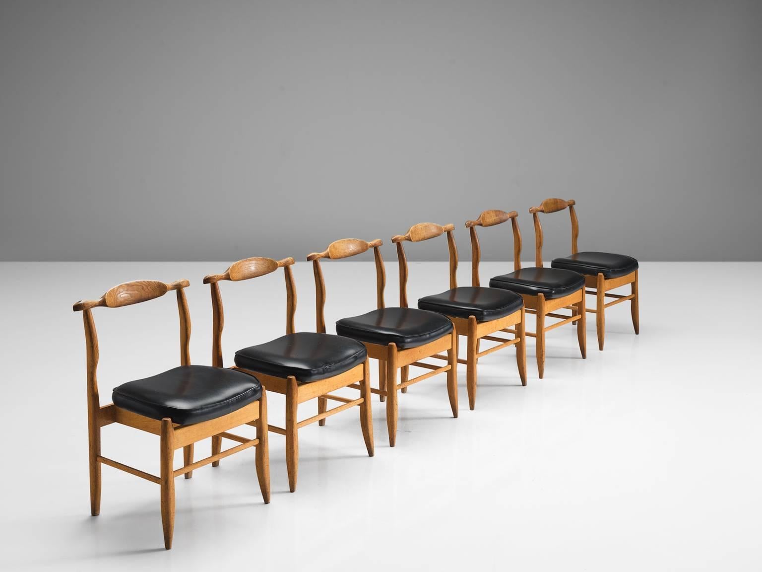 Guillerme & Chambron, set of six dining chairs, in oak and black faux leather, France, 1960s.

Set of six elegant dining chairs in solid oak by Guillerme and Chambron. These chairs show the characteristic frame of this French designer duo. Tapered