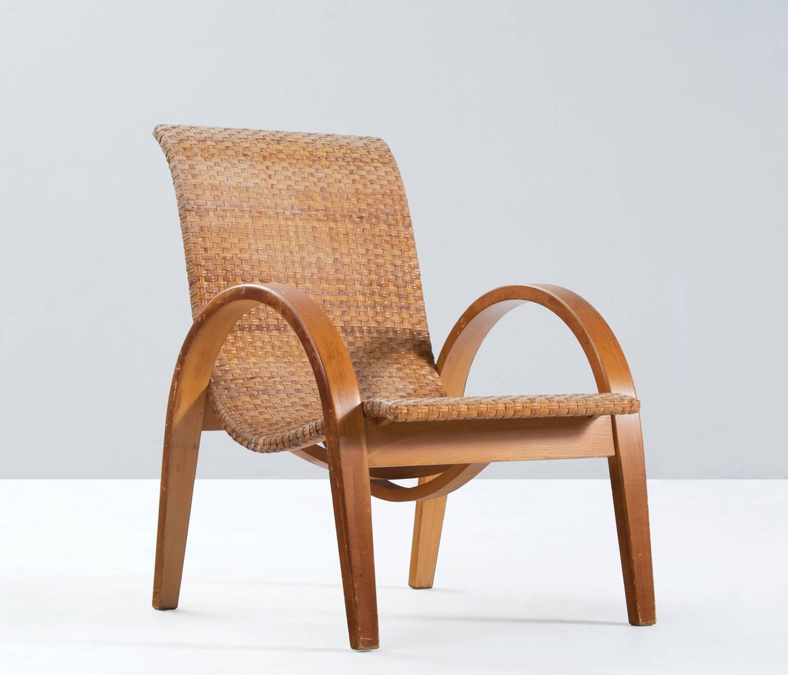 Beautifully curved armchair in solid beech wood, France 1950s.

The solid bent beech wooden frame shows lovely lines, and an interesting construction underneath the seat. The frame has a well made wicker seat element.

Due to the well designed