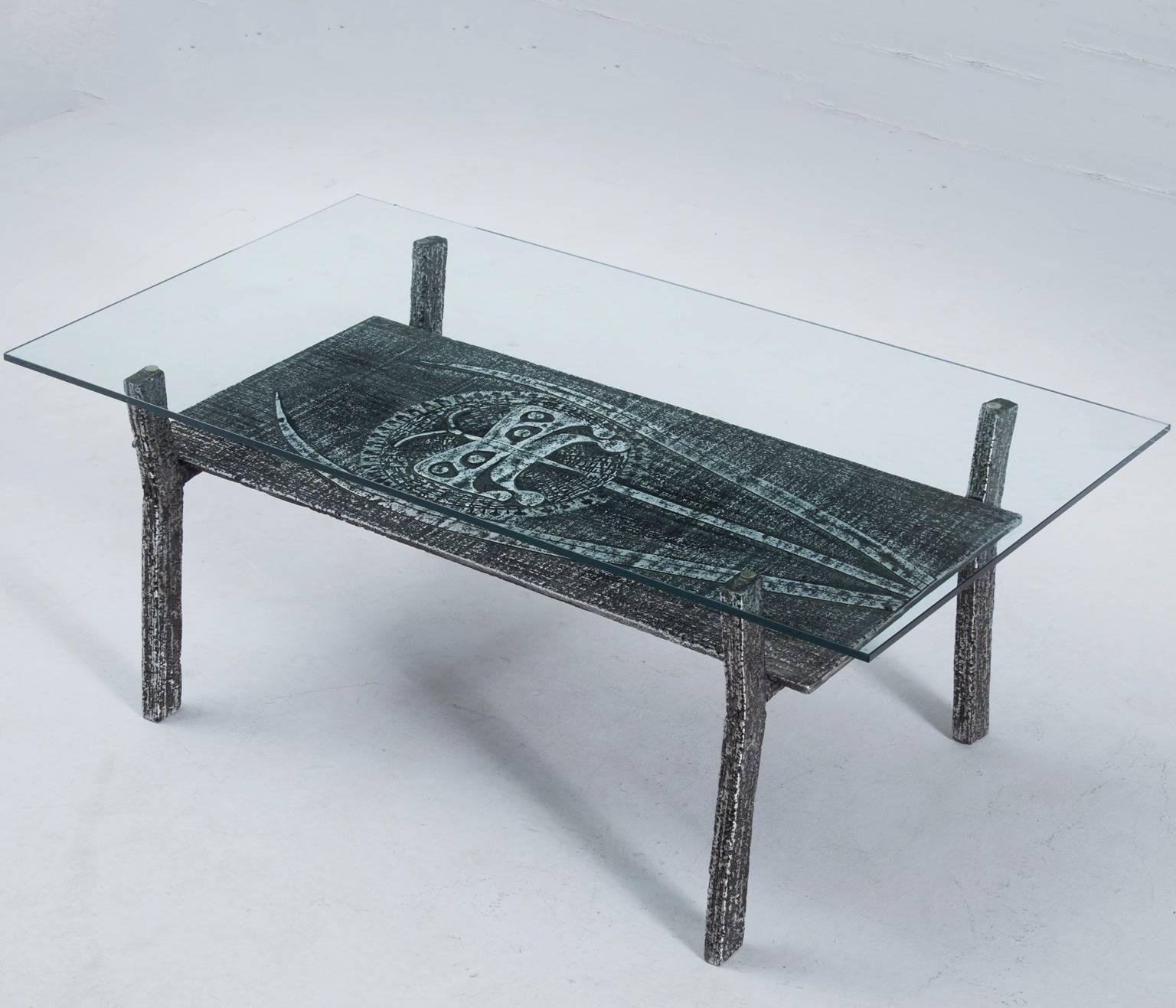 Interesting Brutalist coffeetable in cast iron and glass, Belgium 1970s.

The table has a well sized glass top and a lower top suitable for keeping magazines. The sincere, rough surface of the sand cast piece has a beautiful resin like structure