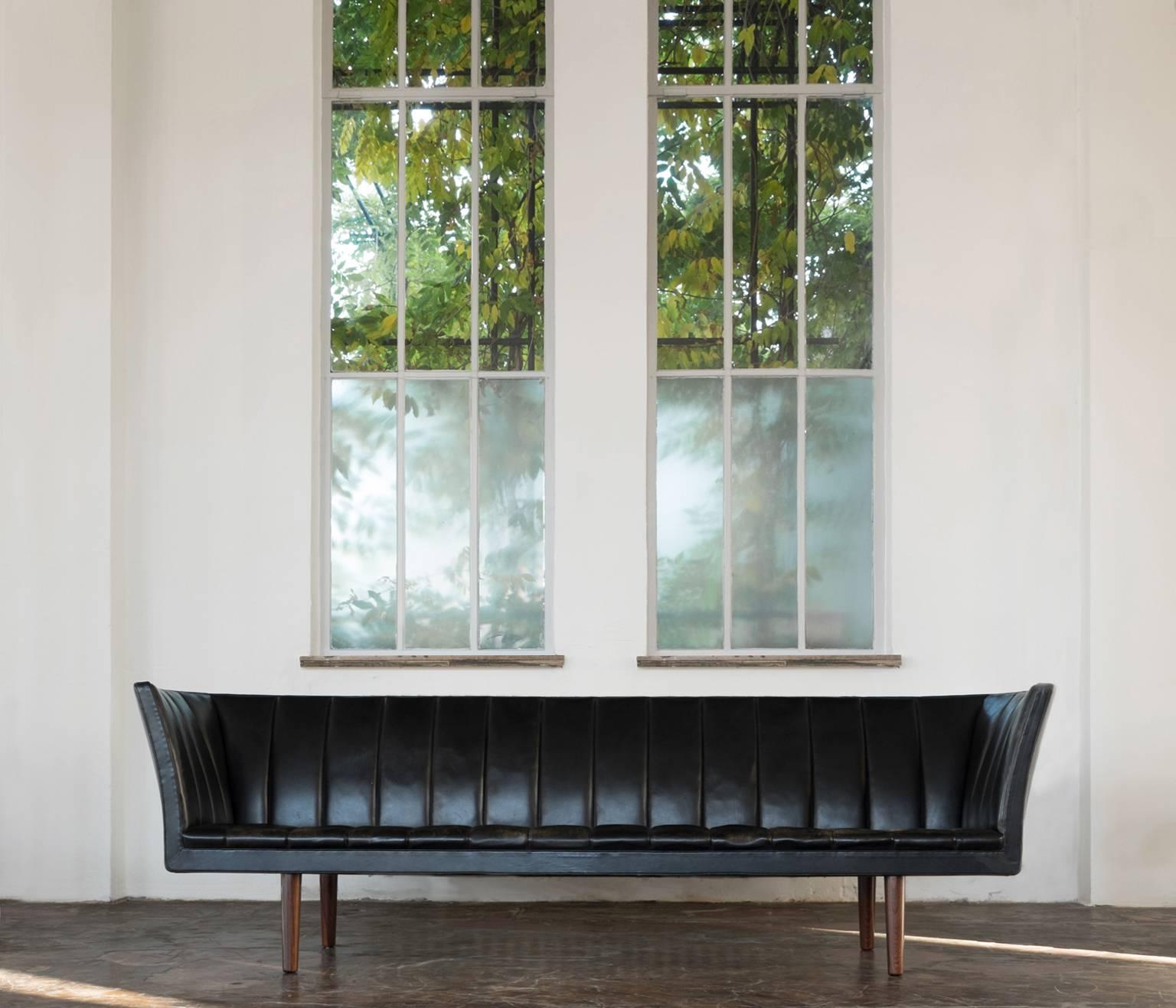 Sofa model V60, in leather and rosewood, by Helge Vestergaard Jensen for Peder Pederson, Denmark 1960. 

Rare three-seat sofa in black leather. High on its tapered rosewood legs, this sofa is a beautiful sight to behold. Upholstered in black