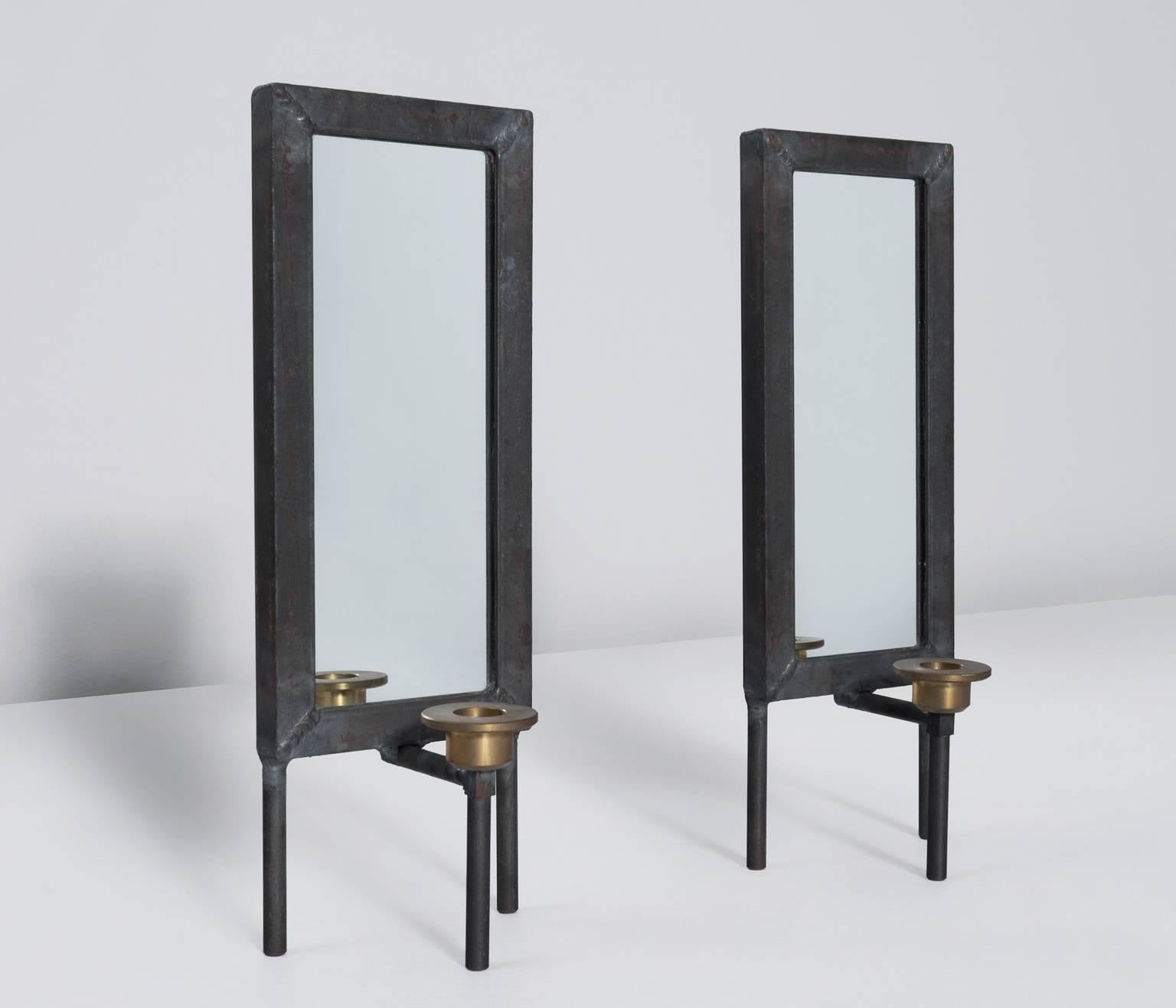 Pair of two unusual decorative candle holders made of an iron frame.

Accompanied with mirrors which reflexes the flame creating a decorative effect.
The round brass holders are placed in squared frames. The frames suggest an open window, instead