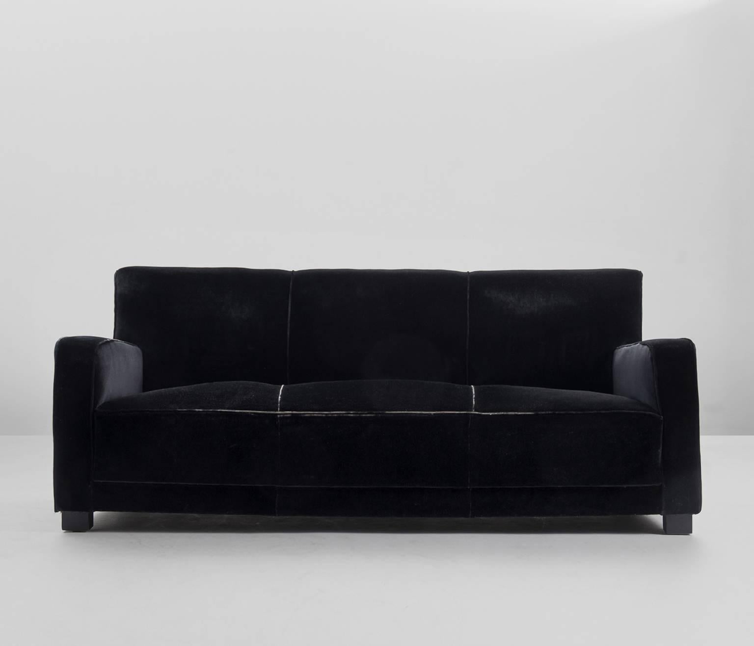 Large three seater sofa.

The back and the seat consists of two one part. The armrests are elegantly shaped. The legs are made from dark stained wood.

The sofa show very elegant lines.
Currently upholstered in original black velvet fabric,