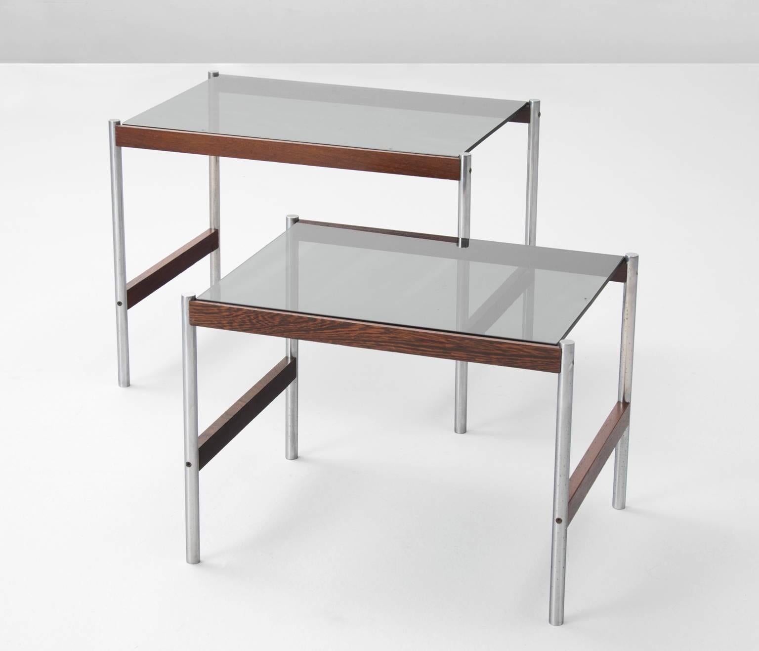 These lovely versatile nesting tables are beautifully composed of various materials such as brushed steel and wood, accompanied with smoked glass table tops. Designed by Artifort, the Netherlands 1960s.

Due to the subtle design the tables appear