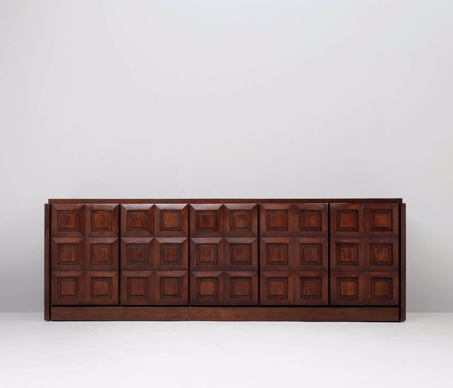 Brown Brutalist credenza, European 1970s.

Large Brutalist credenza in oak veneer with graphical designed doorpanels.
Five doorpanels, each with a three-dimensional pattern of six squares, wich gives the cabinet a very strong expression.
 
The