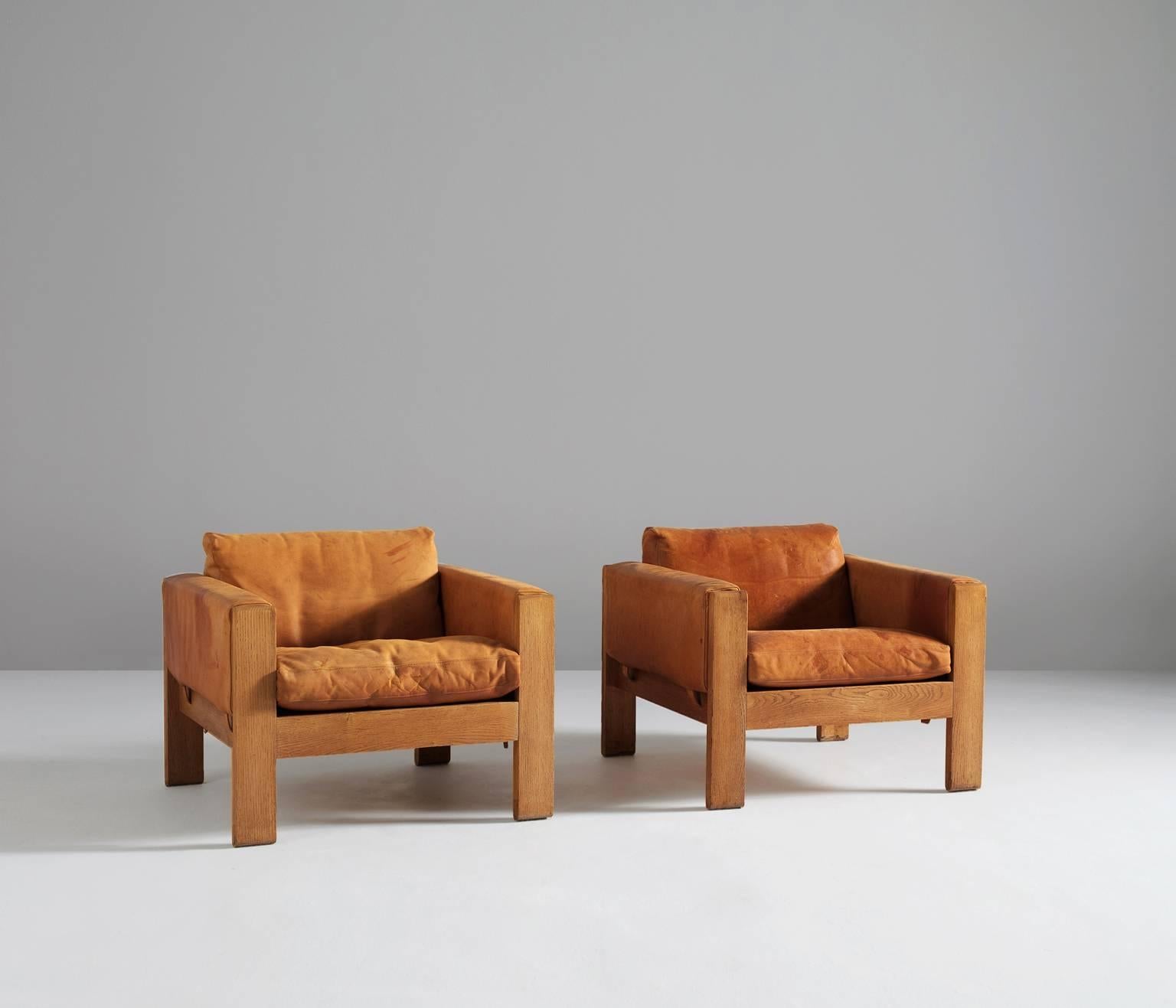 Pair of lounge chairs in oak and cognac leather, Denmark, 1960s.

A pair of comfortable cognac leather easy chairs. These lounge chairs holds a solid crafted oak frame in a nice cubic design. The seating and back are with dawn filled cushions. The