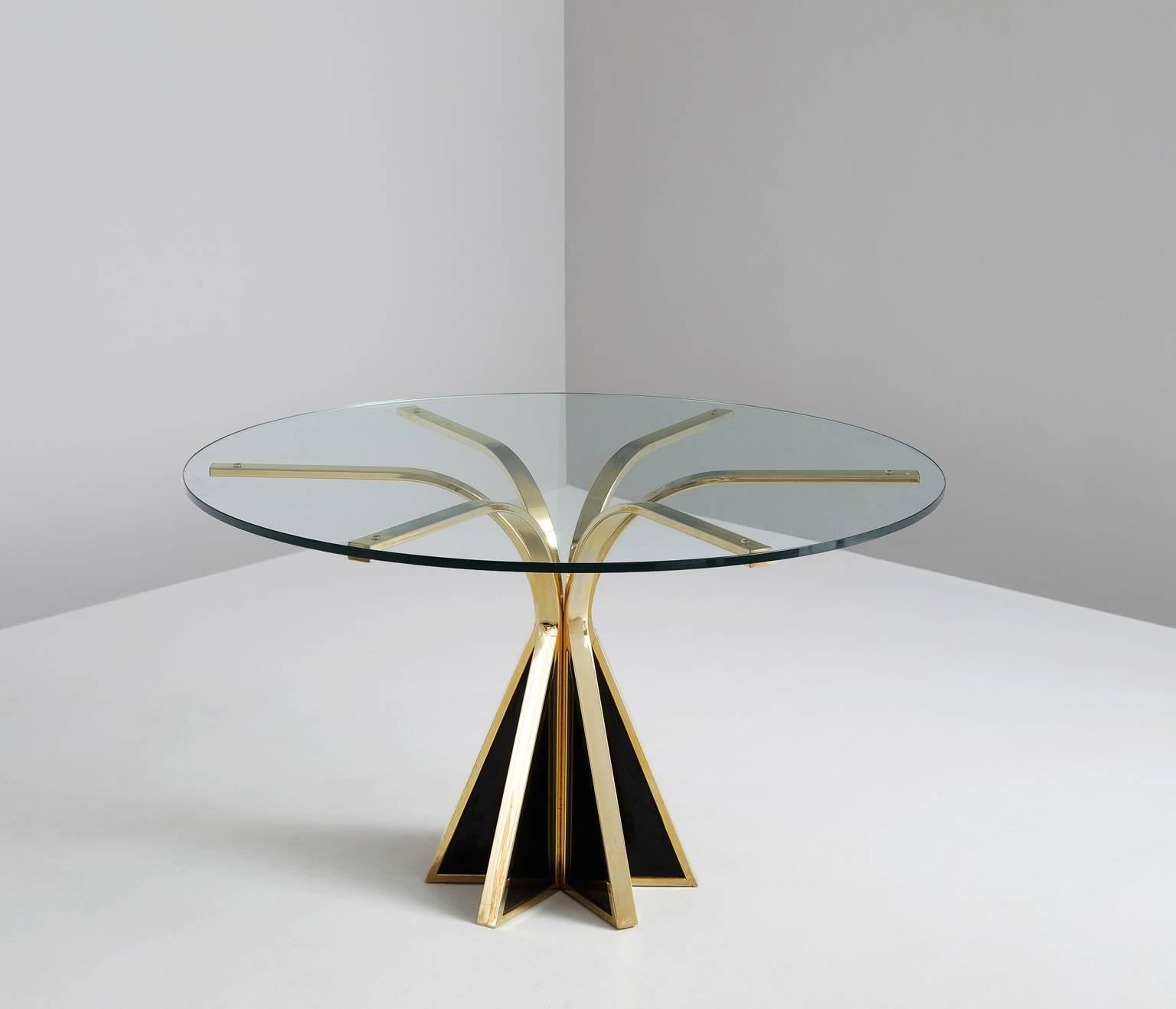 Round dining table in glass and brass, Italy, 1970s. 

Elegant dining table with round glass top. The top rests on a base of six brass straps, which fluently run into the legs of the table. This table show some nice contrasts; the clear glass and