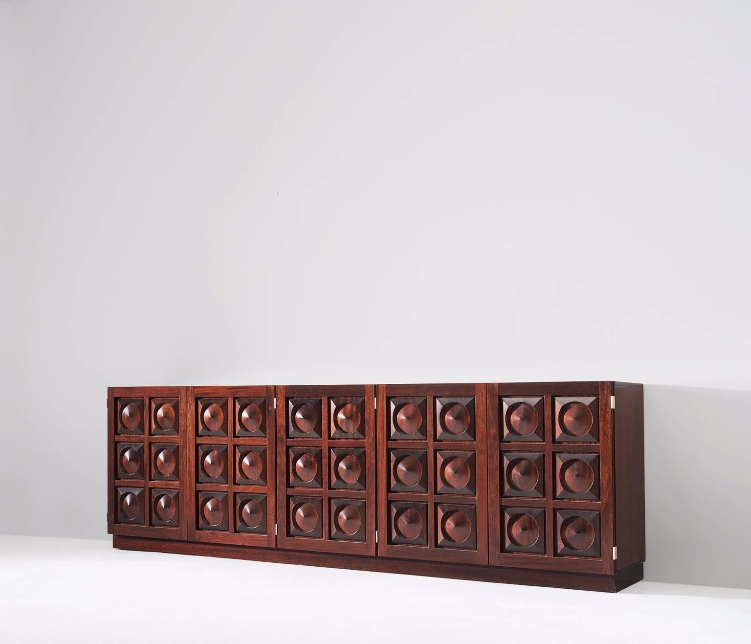 Brown Brutalist credenza in mahogany, European 1970s. 

Sturdy credenza in mahogany with graphical designed door panels. Five-door panels, each with a three-dimensional pattern of circles and squares, which gives the cabinet a very strong