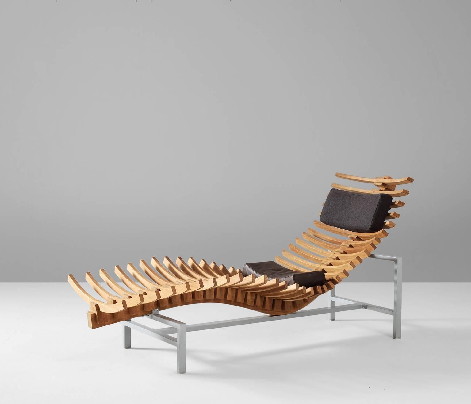 Chaise longue in teak and aluminium, Netherlands, 1980s. 

Exceptional chaise longue. The seating of this chaise consists of teak slats. They are arranged to form a skeleton, with a backbone on the lower side. Two cushions to provide more comfort.
