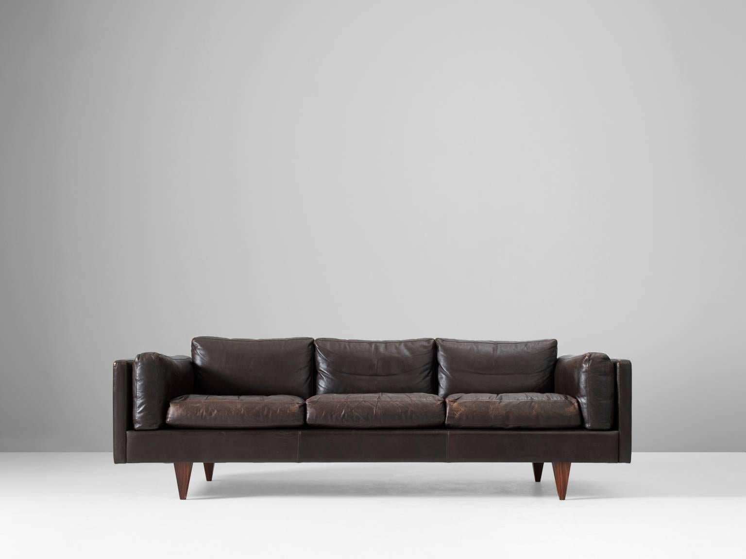 Three-seater sofa, brown leather and wood, by Illum Wikkelso, Denmark 1960s. 

This sofa is one of the best mid-century designs to be found in Denmark. It shows great craftsmanship and is in a wonderful condition. Due to the luxurious down filled