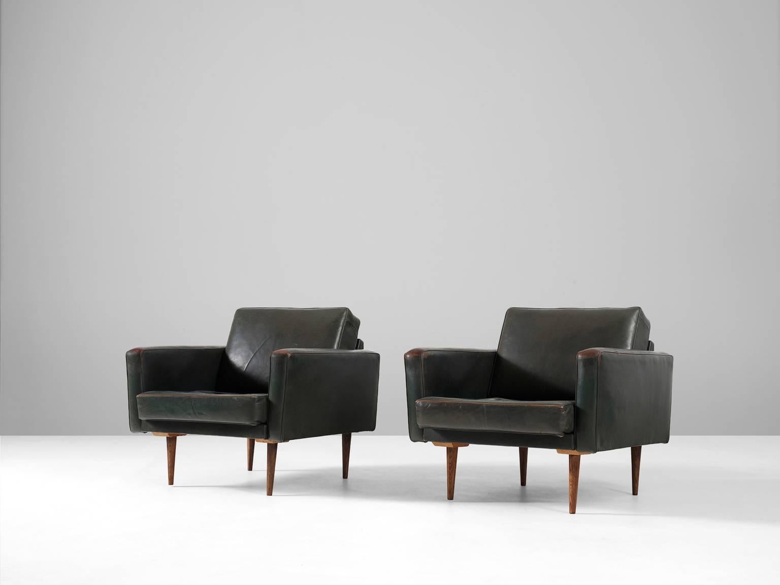 Armchairs, in leather and rosewood, Italy 1960s.

Pair of lounge chairs in dark green leather. The leather upholstery of these easy chairs shows a beautiful patina, which gives these chair a vibrant appearance. 
Due the tapered wooden legs, these