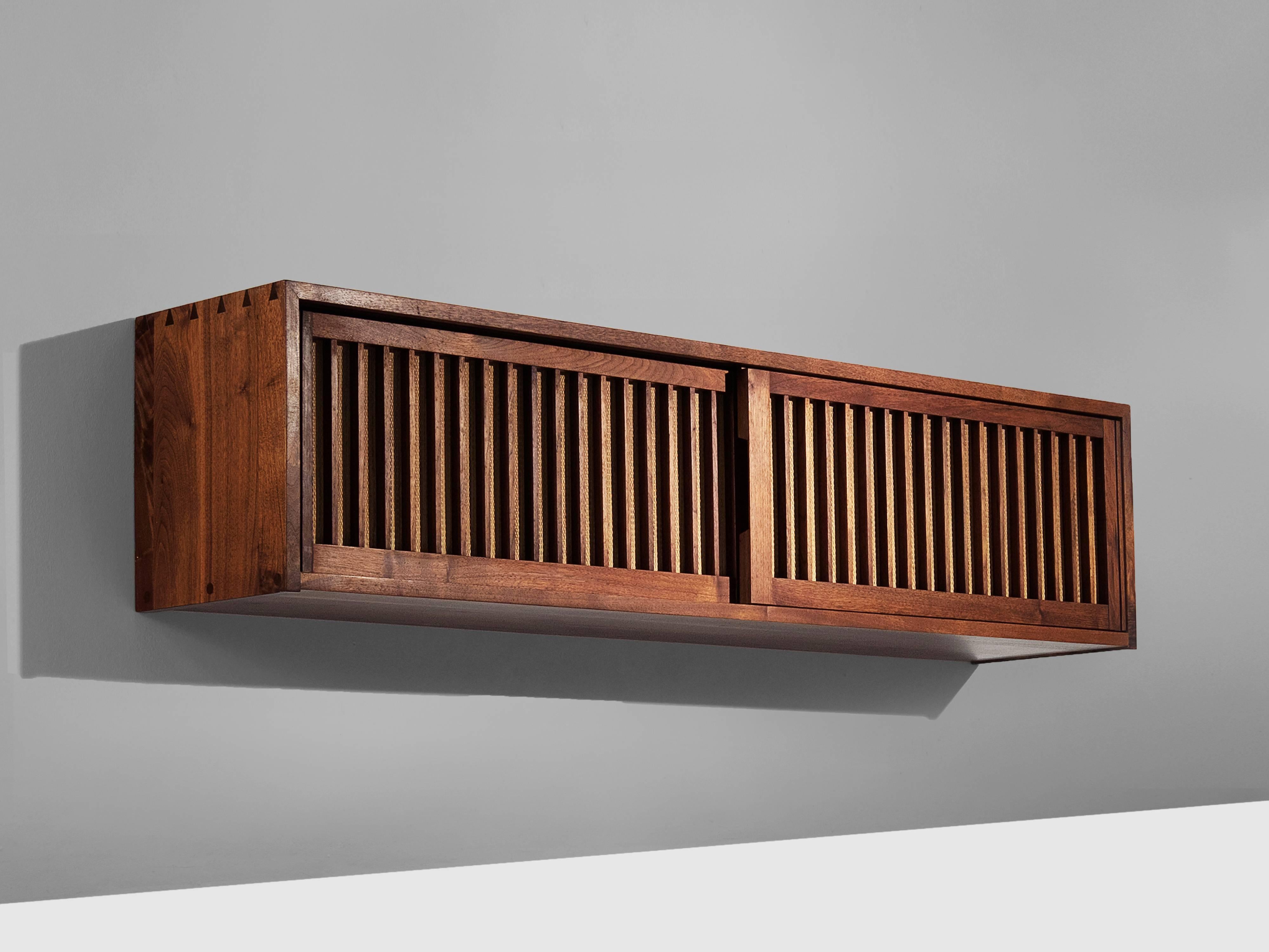 Cabinet, in walnut, oak and pandanus, by George Nakashima, United States 1960s. 

Exceptional cabinet by master woodworker George Nakashima. This wall-mounted case has two spindle sliding doors with pandanus cloth. The cabinet shows the great