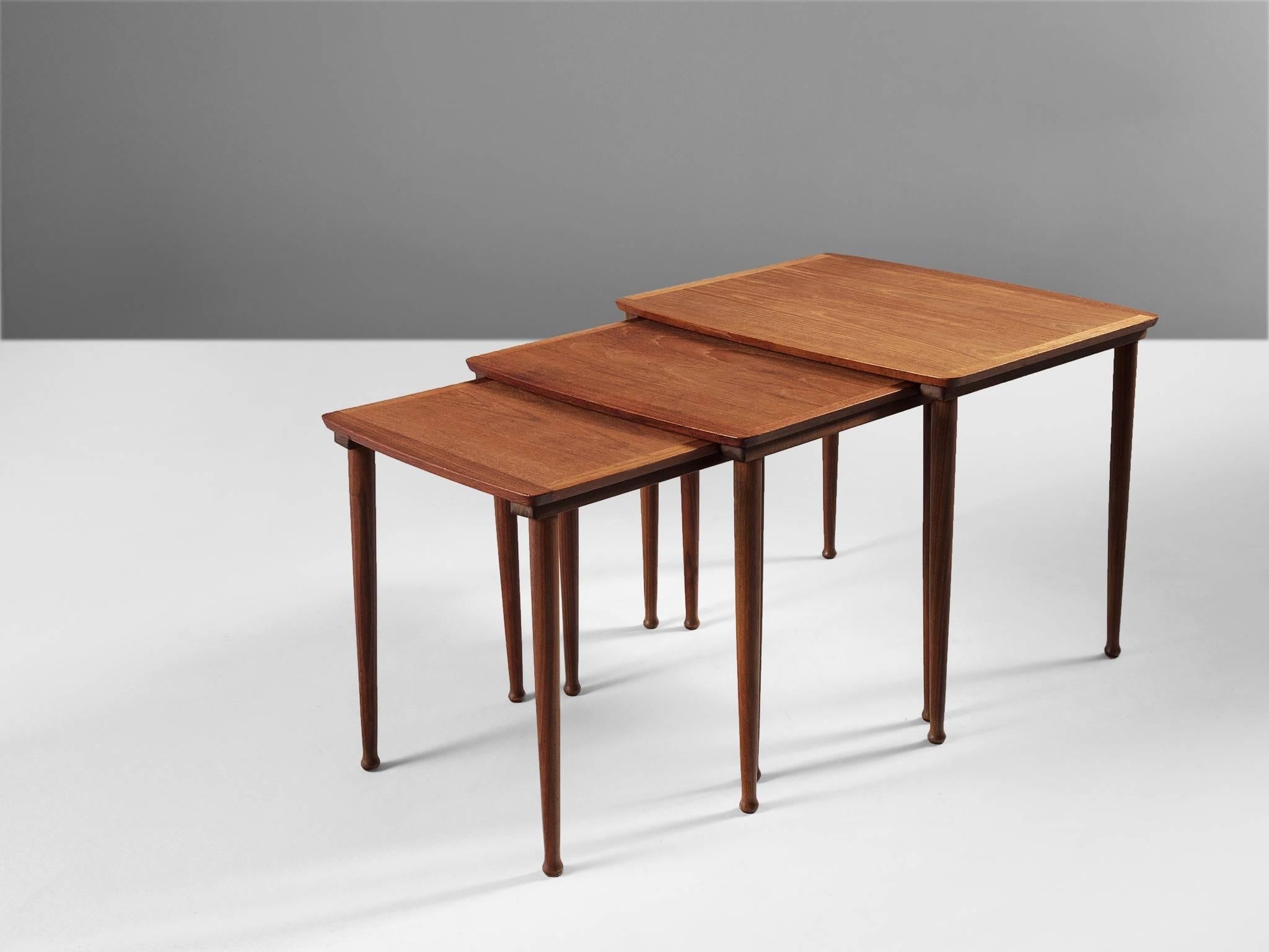 Set of three nesting tables, in teak, Scandinavia, 1950s.

Elegant set of three nesting tables. Each tables has a rectangular top with a nice trim. The cylindrical legs are tapered with a round thickening at the end. The teak has a beautiful warm
