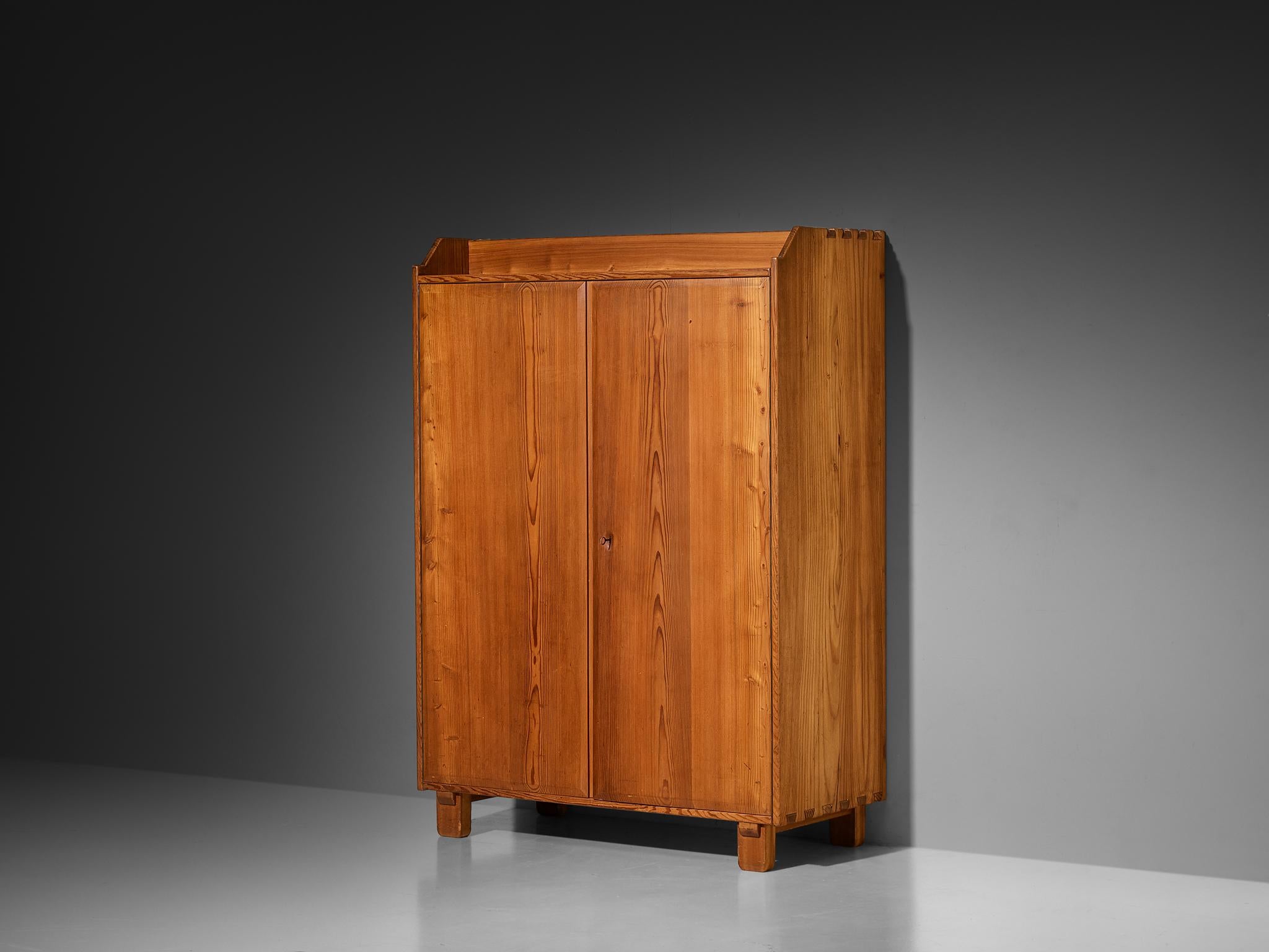 Cabinet, pine, brass, France, 1960s

This two-door cabinet shows a sturdy, grounded presence. The doors can be closed and opened with a key used as a handle. The inside provides great storage space. The wood joints specialize the design and