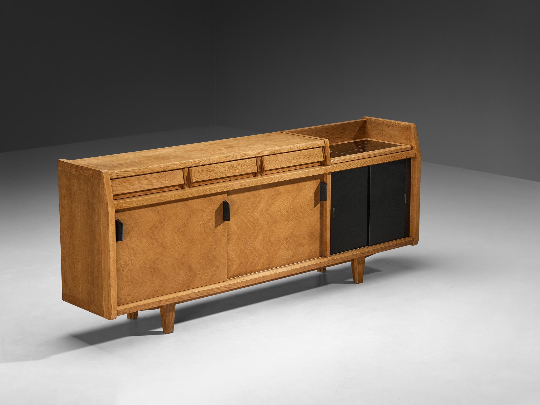 Guillerme et Chambron for Votre Maison, sideboard, solid oak, glass, ceramic, France, 1960s

This credenza in oak, designed by the French duo Guillerme & Chambron, offers a confident and joyful statement in mid-century modern design. At once