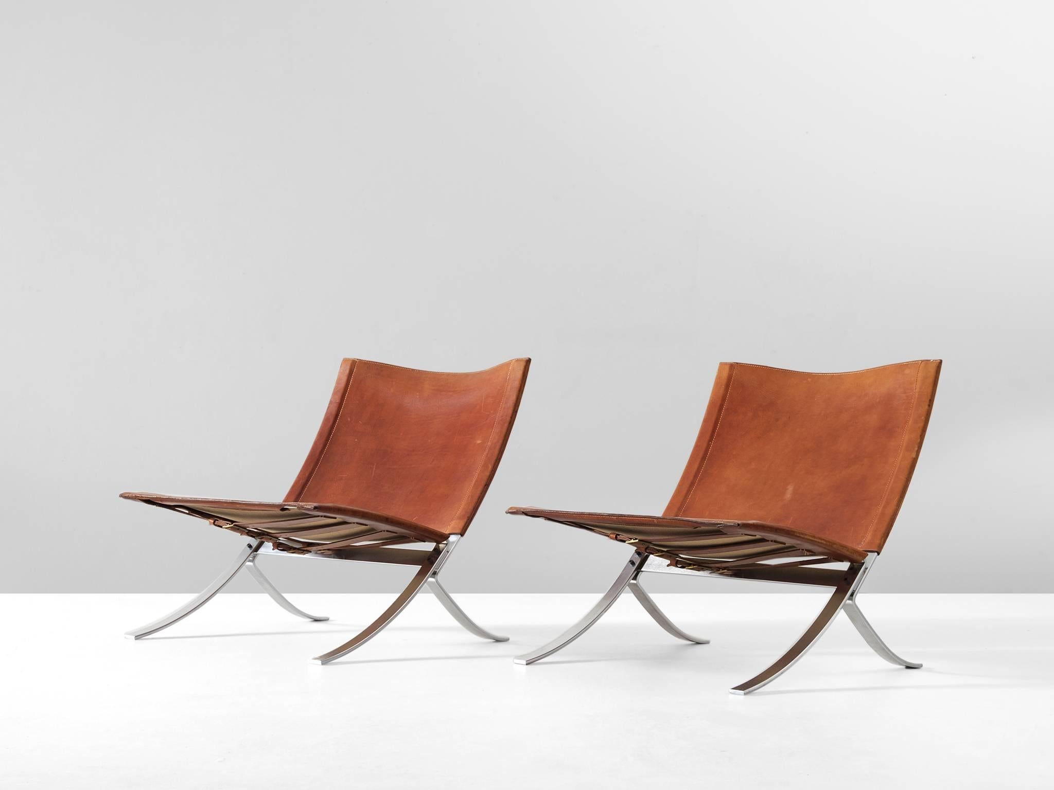 Set of two lounge chairs, in steel and leather, by Steen Østergaard, Denmark, 1960s. 
 
Modern pair of X-chairs in steel with cognac leather upholstery. These chairs have an elegant yet highly simplistic design. The frame consist of steel strips