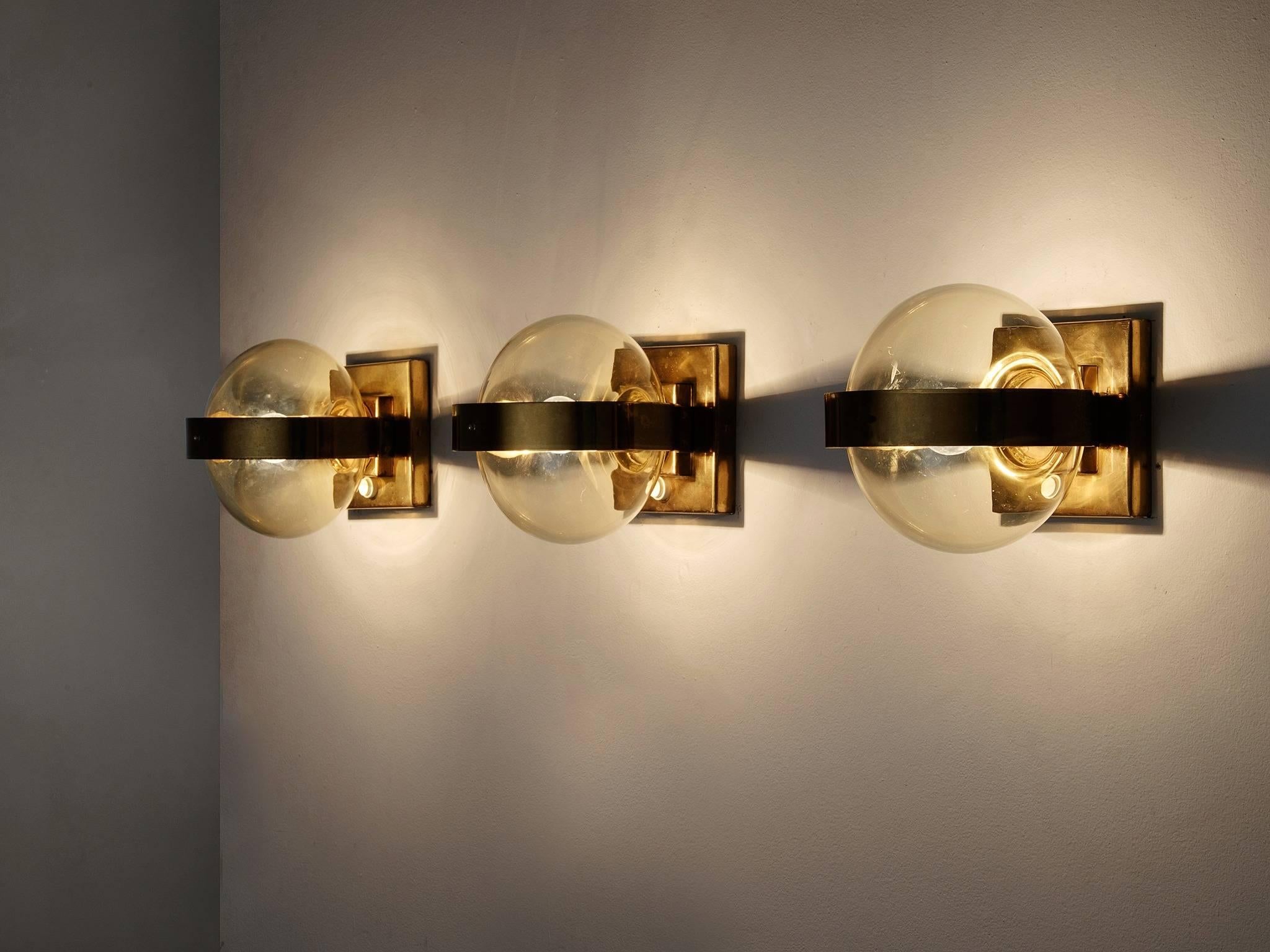 Set of two wall lights, in brass and glass, Europe 1970s.

Set of sconces with beautiful colored glass spheres. Fixture in shining brass, in addition of a brass ring around the glass shade. Each globe shaped sphere is made from clear glass and is