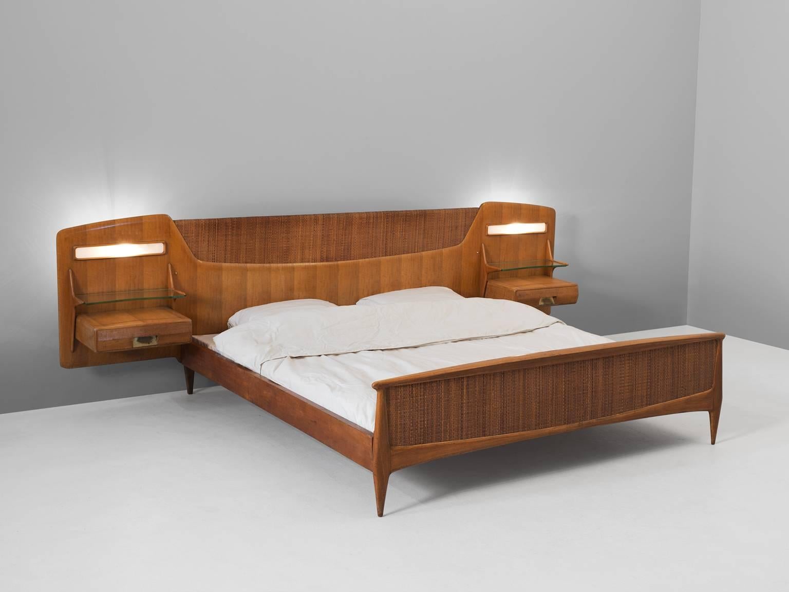 Double bed, in birch, cane and glass, Italy, 1950s. 

Mid century modern illuminated bed with floating nightstands and lights. The head shows beautiful shapes, which are repeated in the beds frame. The nightstands have a drawer and glass shelve.