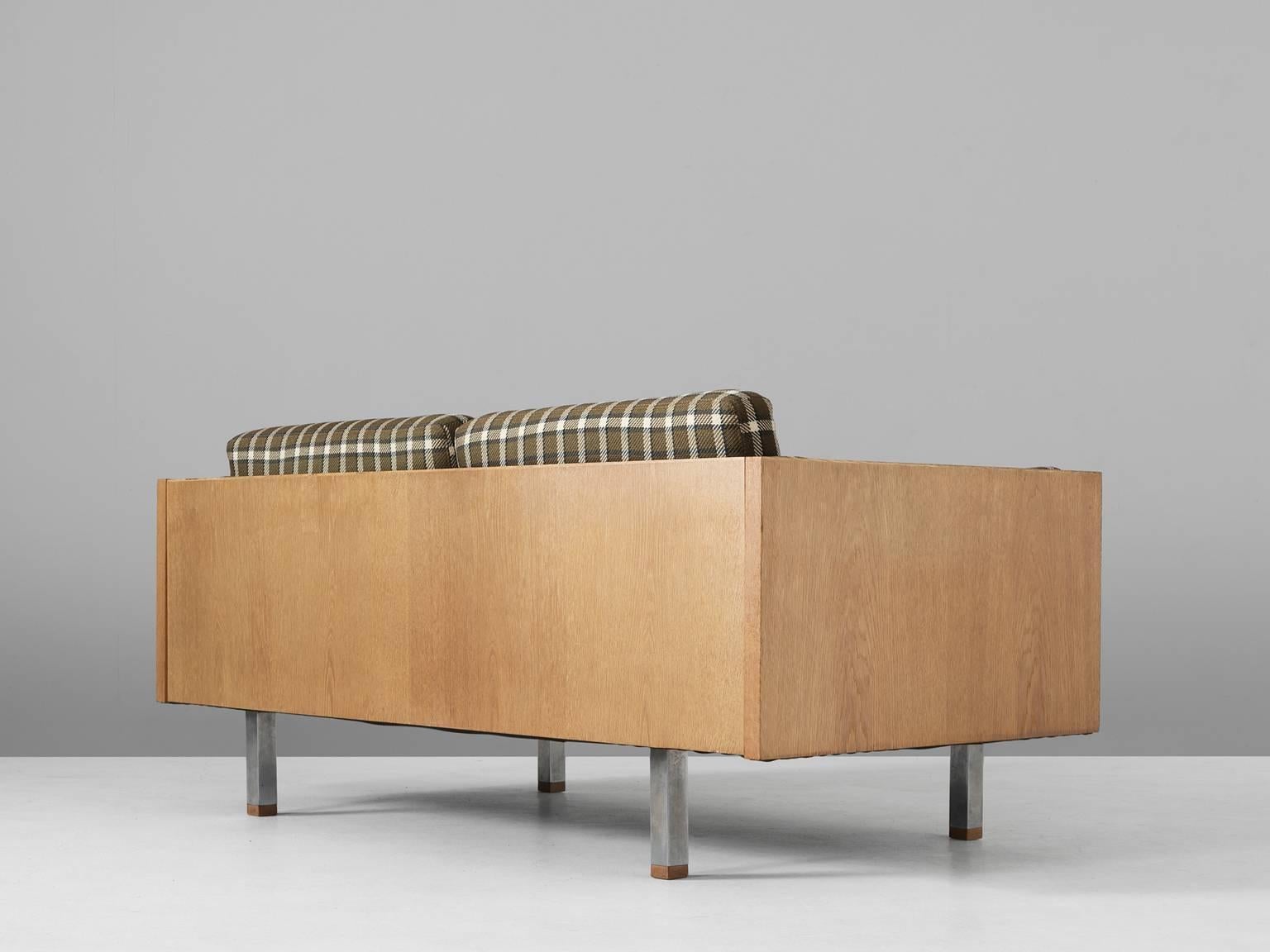 Two-seat sofa, in oak, metal and fabric, Denmark, 1960s. 

Scandinavian two-seat sofa. The frame consist of oak with cubic metal legs, which provide an open look to the quite solid seating. All sides are covered with wood and show the beautiful