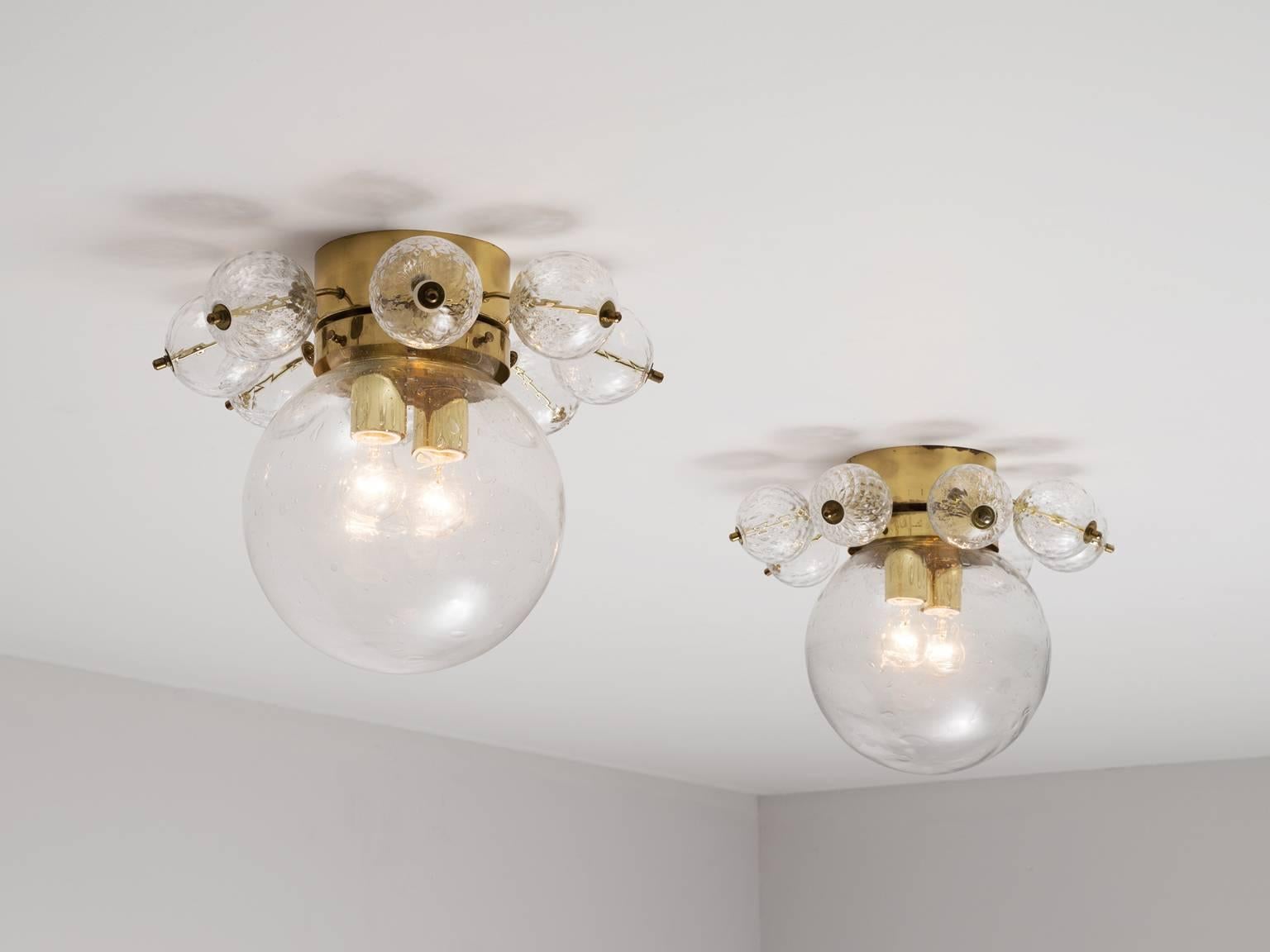 Set of two ceiling lights in glass and brass, Europe, 1970s.

Pair of ceiling lights in brass and structured glass. Consisting of one large sphere of slightly structured glass with two-light points. Decorated with brass and structured glass